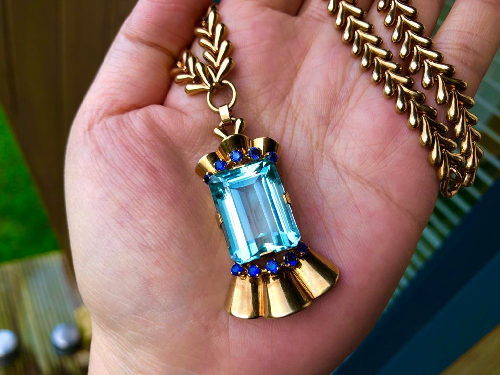 Made in Mid 20th century, this Tiffany necklace features an eye-catching square cut aquamarine accented by circular-cut sapphires; mounted in 14k gold. The chain composed of gold chevron links, length 15 1/2 in.

STONES
Aquamarine: 20 x 15 x 10