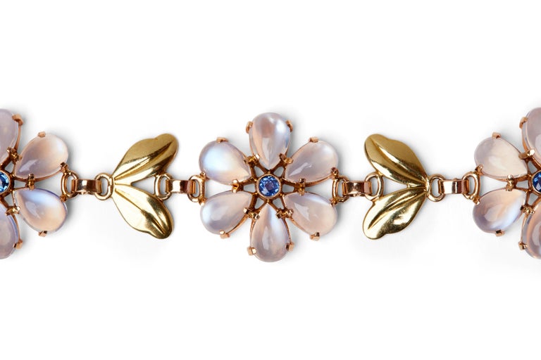 This elegant 1940s bracelet from Tiffany & Co. features three floral motif stations separated by leaf-shaped links. Each flower is composed of luminous cabochon moonstone petals accented by round-cut blue sapphires.

- 7.25” long by 1” wide
-