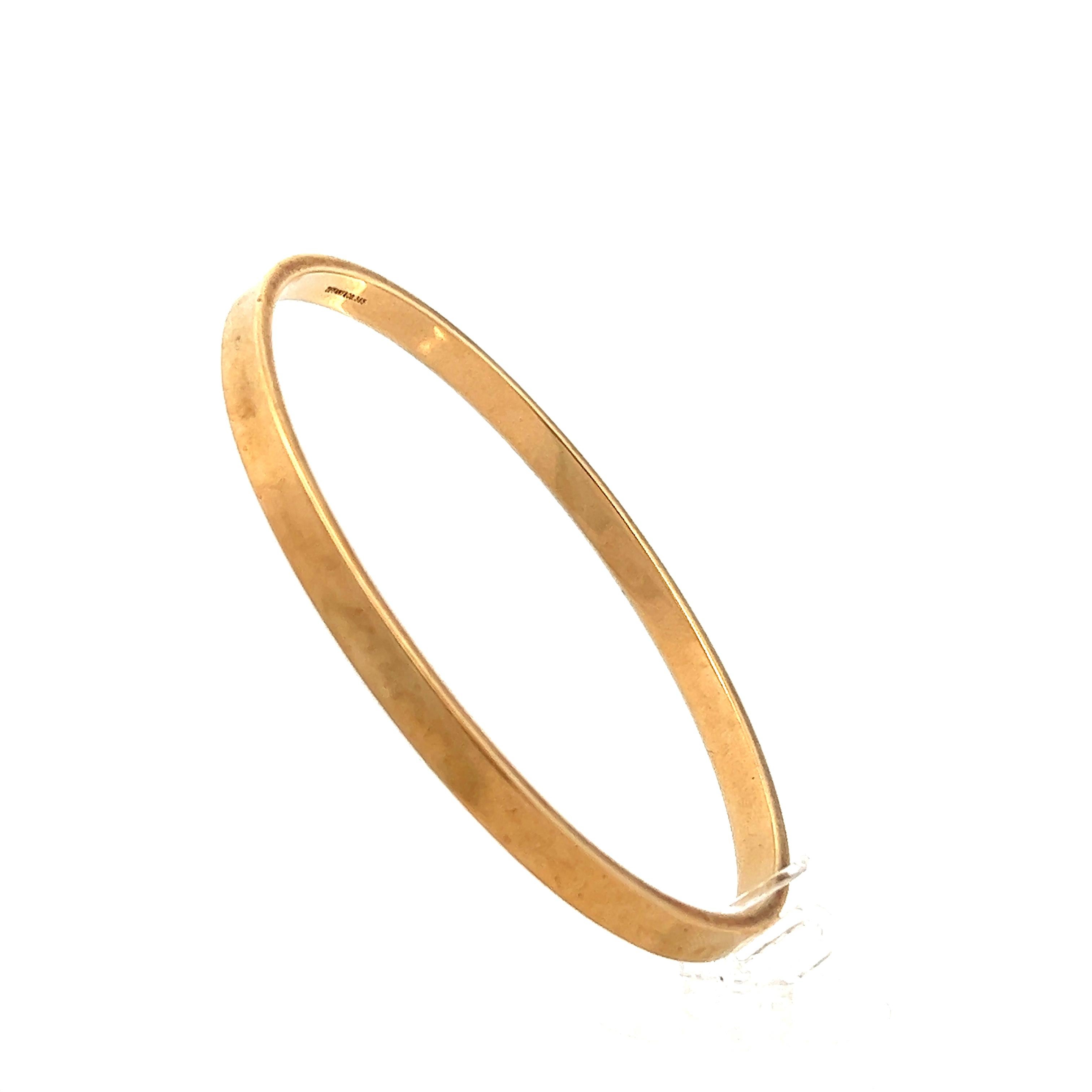 This vintage Tiffany & Co. 14 Karat Yellow Gold Bangle Bracelet is crafted in beautifully detailed 14K polished yellow gold. The bracelet features a traditional slip on bangle design and features no locks or clasps. The inside of the bracelet it