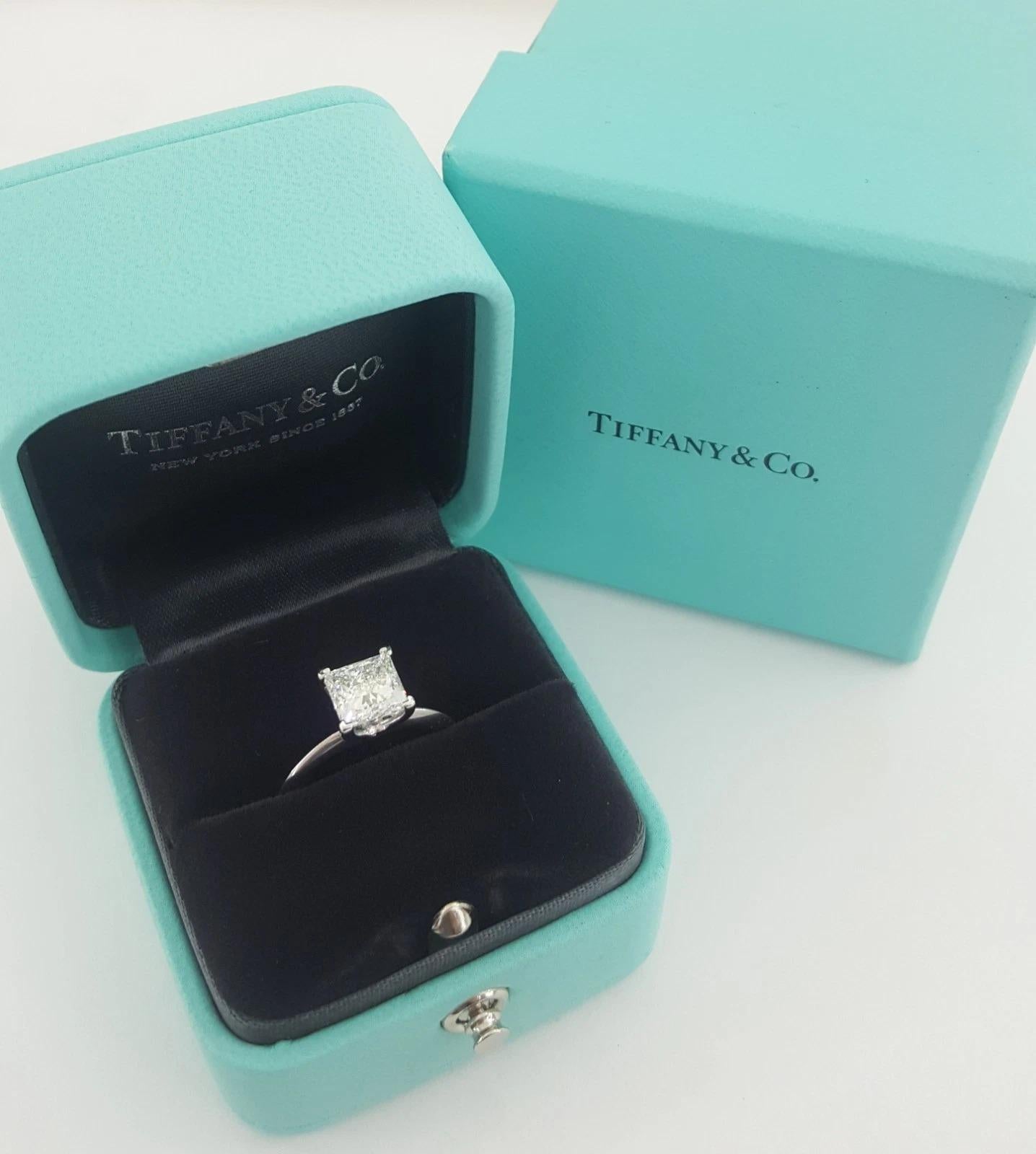 Un icónico anillo de compromiso solitario Tiffany & Co. elaborado en platino, con un impresionante diamante talla princesa brillante de 1,56 quilates. El diamante es de color F, claridad VS2, con talla excelente, pulido excelente, simetría muy buena