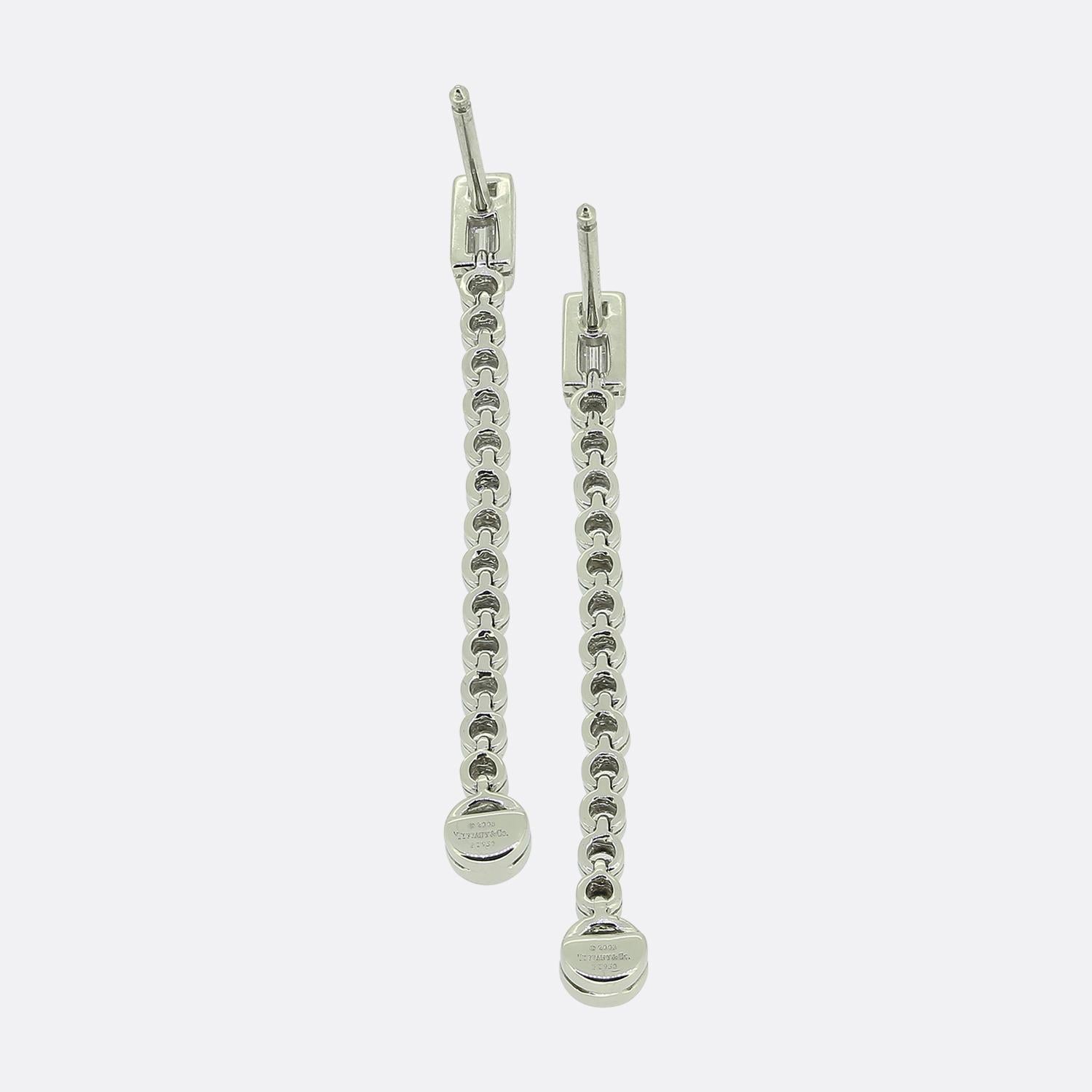 Voici une élégante paire d'Eleg du célèbre créateur de bijoux Tiffany & Co. Méticuleusement fabriquées en platine, ces boucles d'oreilles présentent un arrangement vertical de diamants avec un seul diamant droit de taille baguette au sommet,