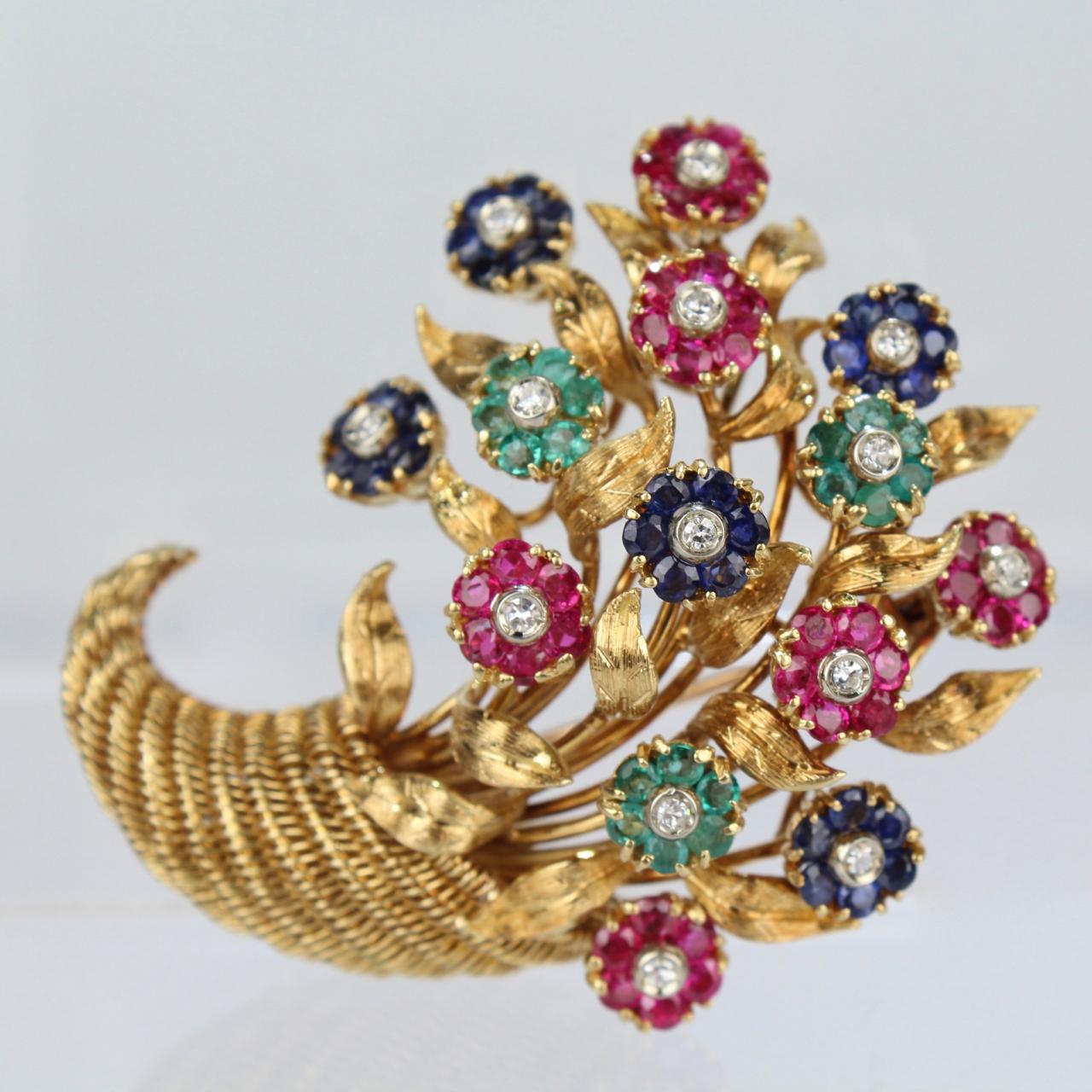A fine and rare Tiffany & Co. 18-karat yellow gold en tremblant brooch set with diamonds, sapphires, rubies, and emeralds.

Simply exquisite with gemstone rosettes, textured gold leaves, and a wirework cornucopia basket.

Each flower trembling
