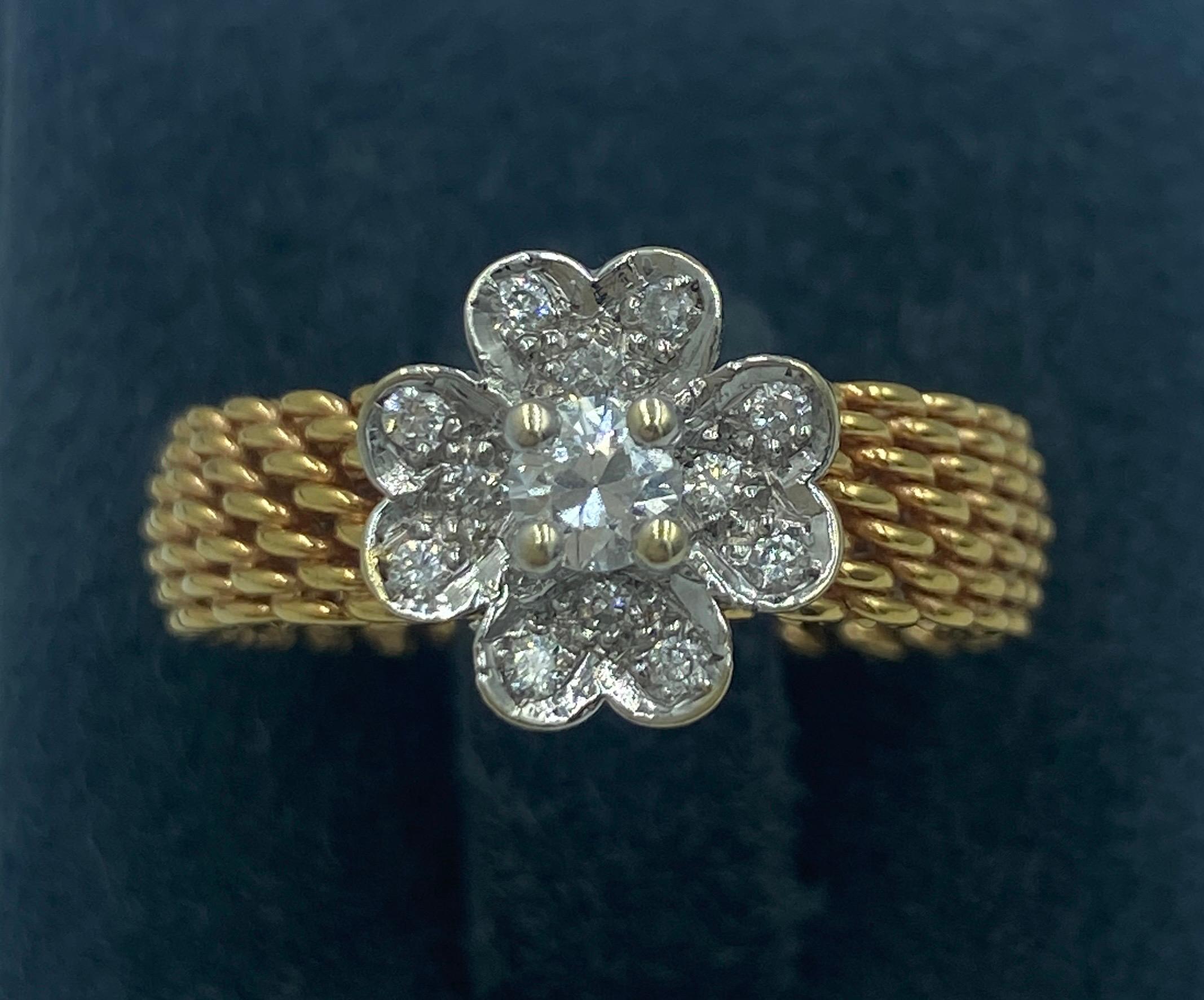 Cette bague Tiffany & Co appartenant à la collection Somerset présente l'anneau en or 18 carats à maille signature mais est ornée d'une fleur en diamant. C'est une pièce délicieuse.
