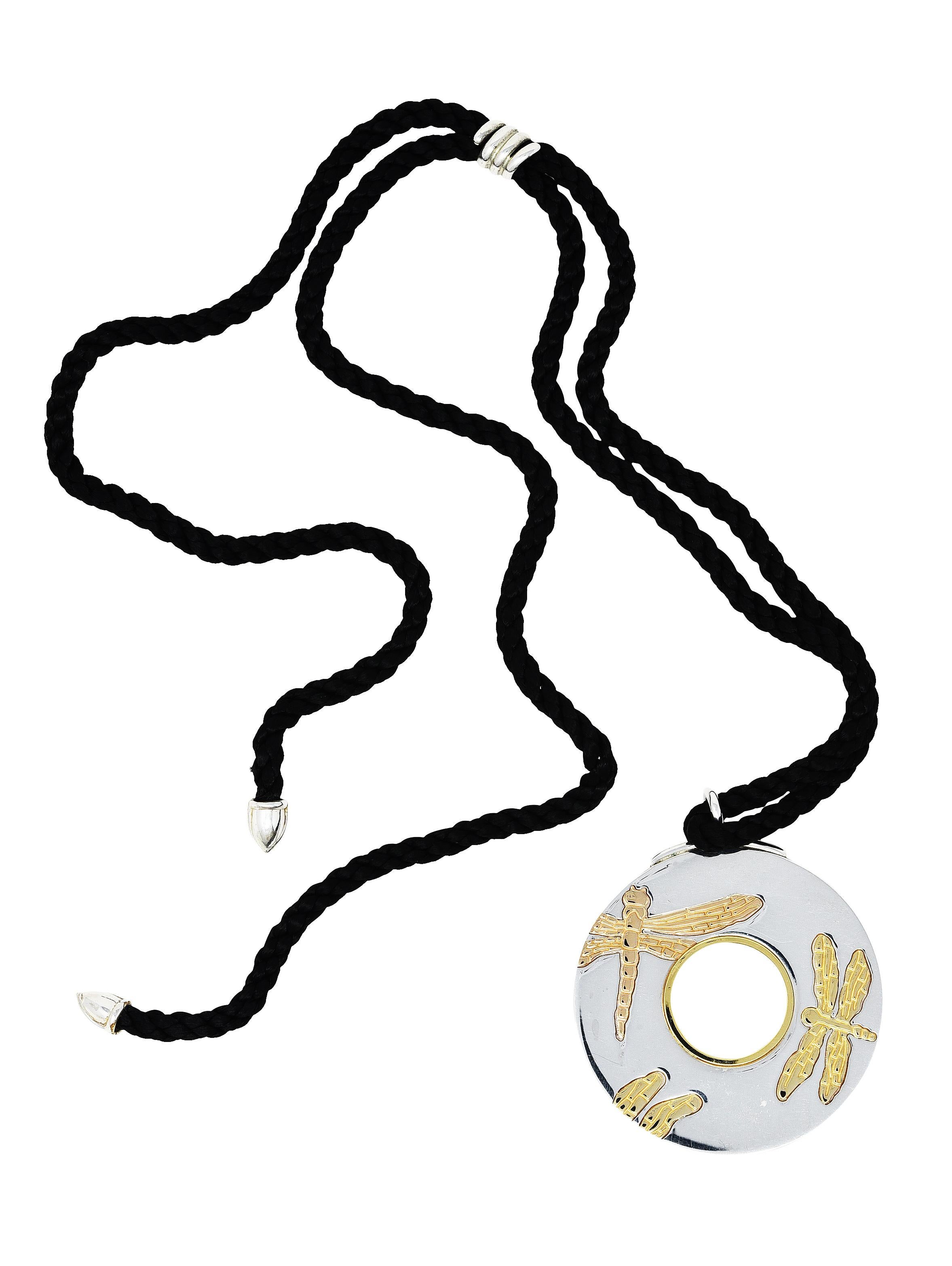 Necklace is designed as a detailed disk pendant suspending from silk chord 

Featuring a high polished silver disk with pierced center 

Accented by engraved gold dragonfly motif and polished gold center ring

Completed by silver bullet terminals