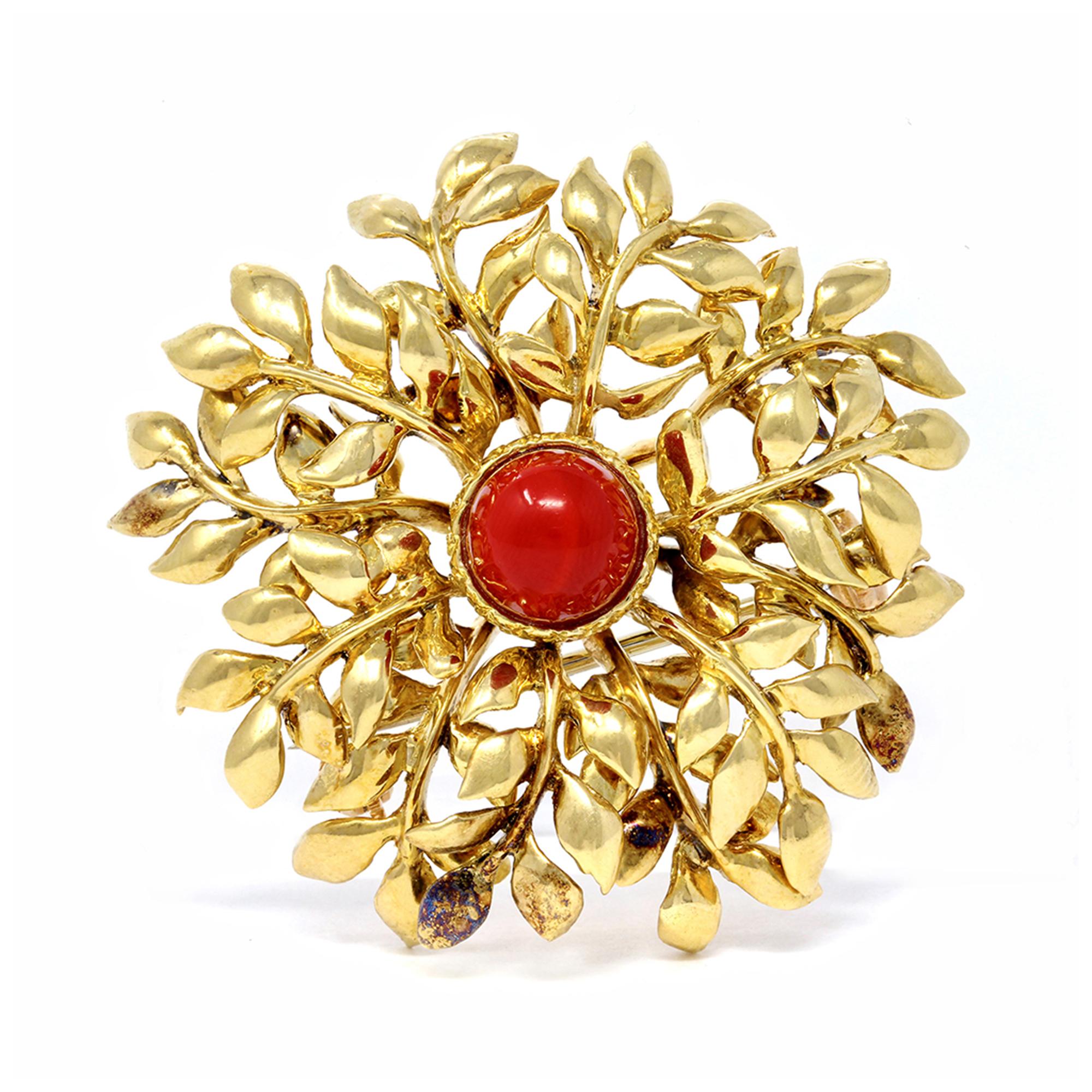 A Signed Tiffany leaf motif brooch with a dome shape coral in the center. This brooch was made in Italy circa 1979 and set in 18 karat yellow gold. The coral cabochon displays a deep red color. The brooch has a total weight of 19.5 grams and