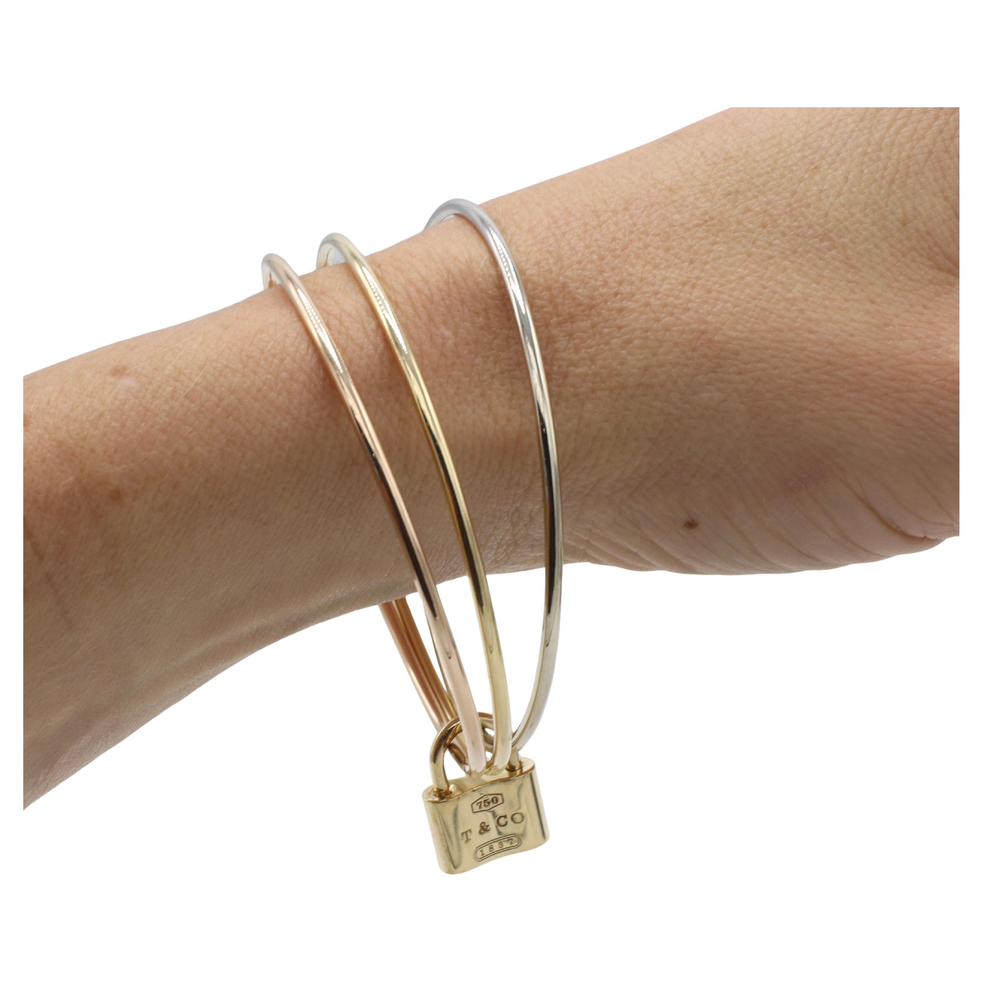 Tiffany & Co. 18 Karat Tri-Color Three Bangle 1837 Lock Bracelet 
Metal: 18k yellow, white, rose gold 
Weight: 37.5 grams
Diameter: 62mm
Circumference: 7.5 inches 
Width: 2mm each bangle 
Lock: 19 x 14.5mm (removable) 
Signed: ©Tiffany & Co. 750 
