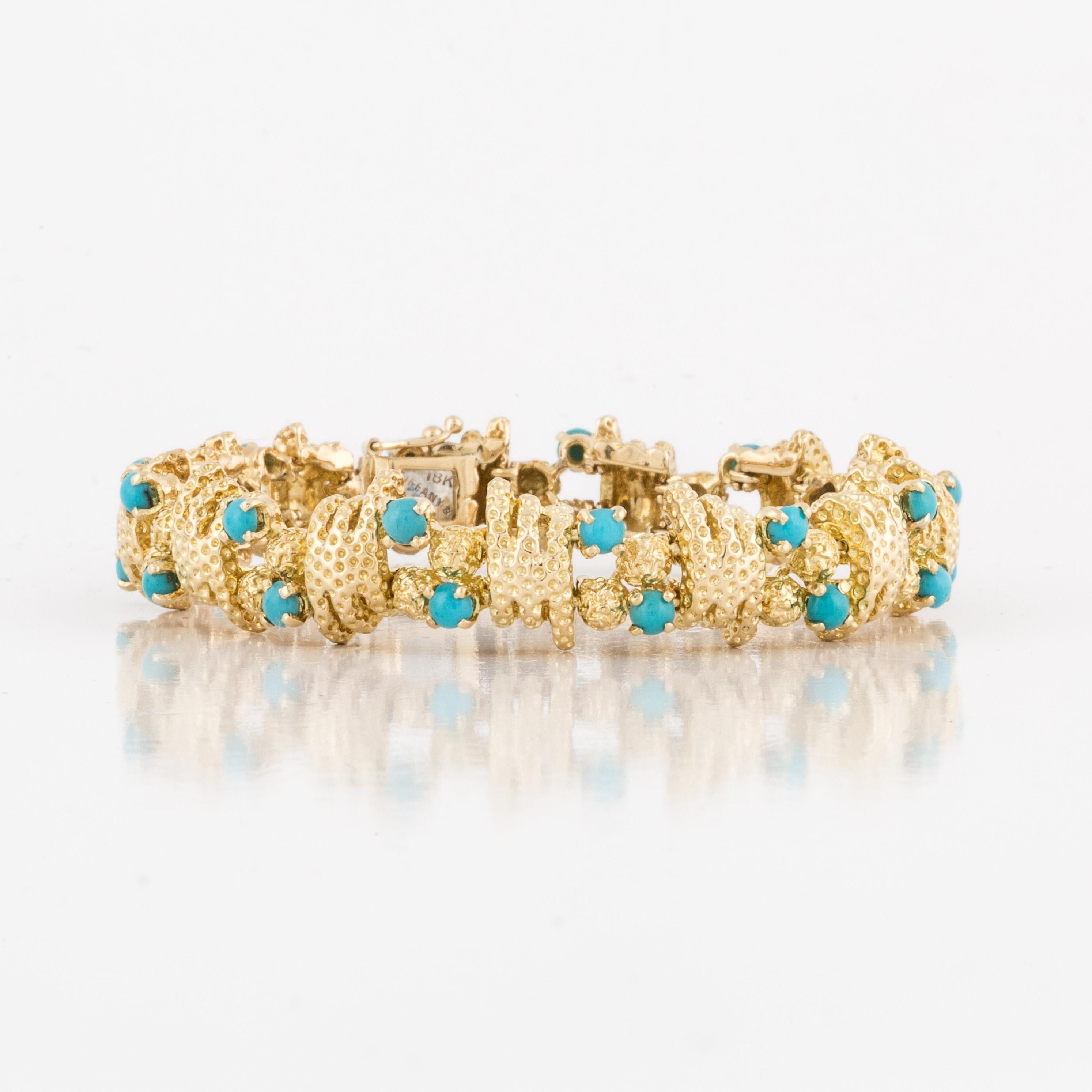 A vintage Tiffany & Co. textured 18K yellow gold bracelet featuring 26 round cabochon turquoise stones.   Circa 1960s.  Measures 7 inches long and 1/2 inch wide.  
