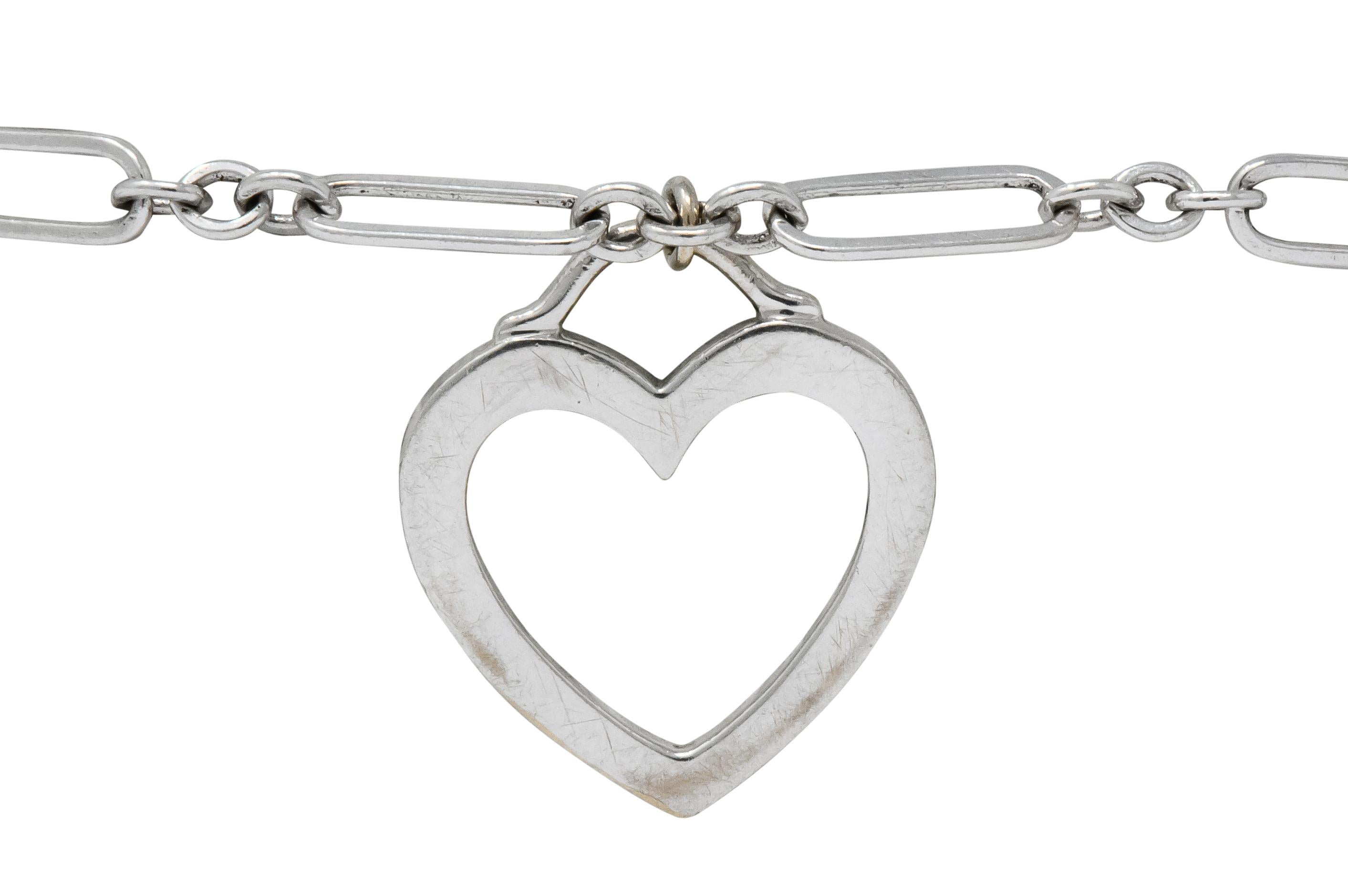 Bracelet features elongated links separated by three jump ring spacer links

With open heart charm suspended by arched bale

Completed by spring ring clasp

Signed Tiffany & Co. and stamped 750, for 18 karat white gold

Length: 7 inches

Heart