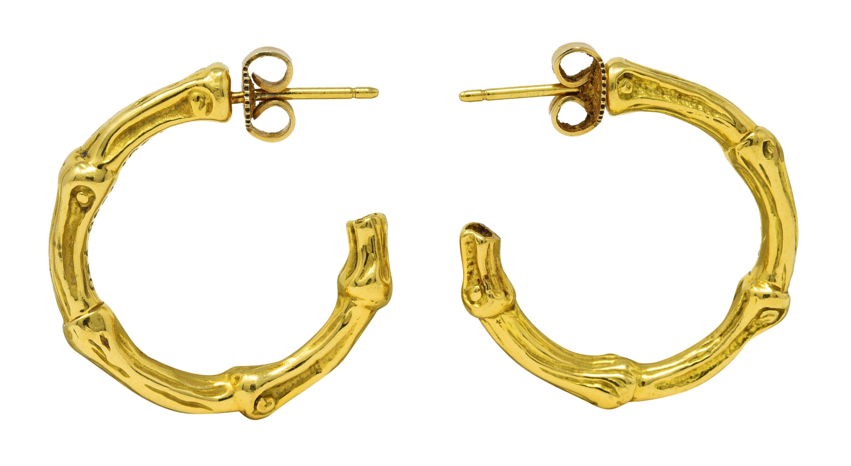 J hoop earrings are designed as stylized bamboo motif. With grooved texture throughout. Completed by posts with friction backs. Stamped 750 for 18 karat gold. With maker's mark for Tiffany & Co.. Circa: stamped 1996. Measures: 1 x 1 inch. Total