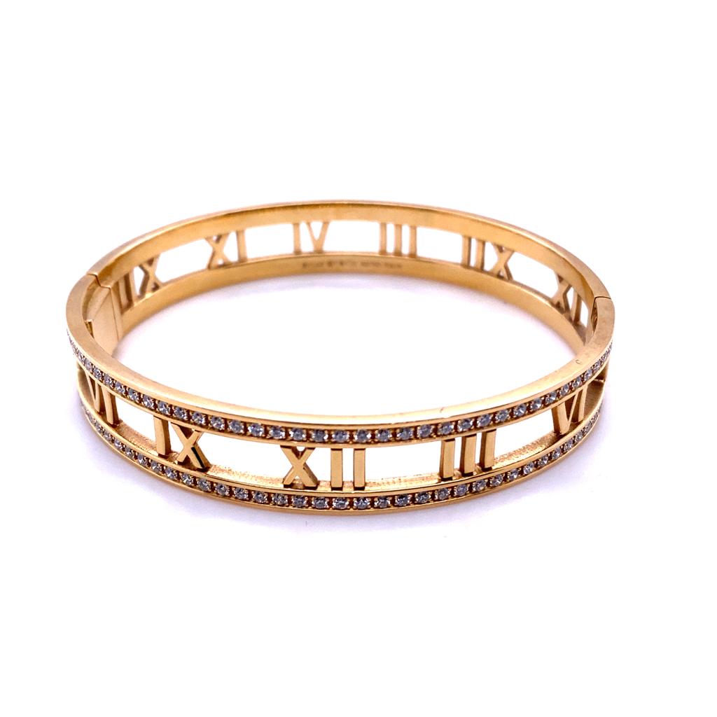 A Tiffany & Co. 18 karat yellow gold diamond Atlas bangle, circa 2015.

From Tiffany & Co's iconic Atlas collection this bangle features an open fret work motif of Roman numerals set to its centre and framed either side by a single of row of pavé