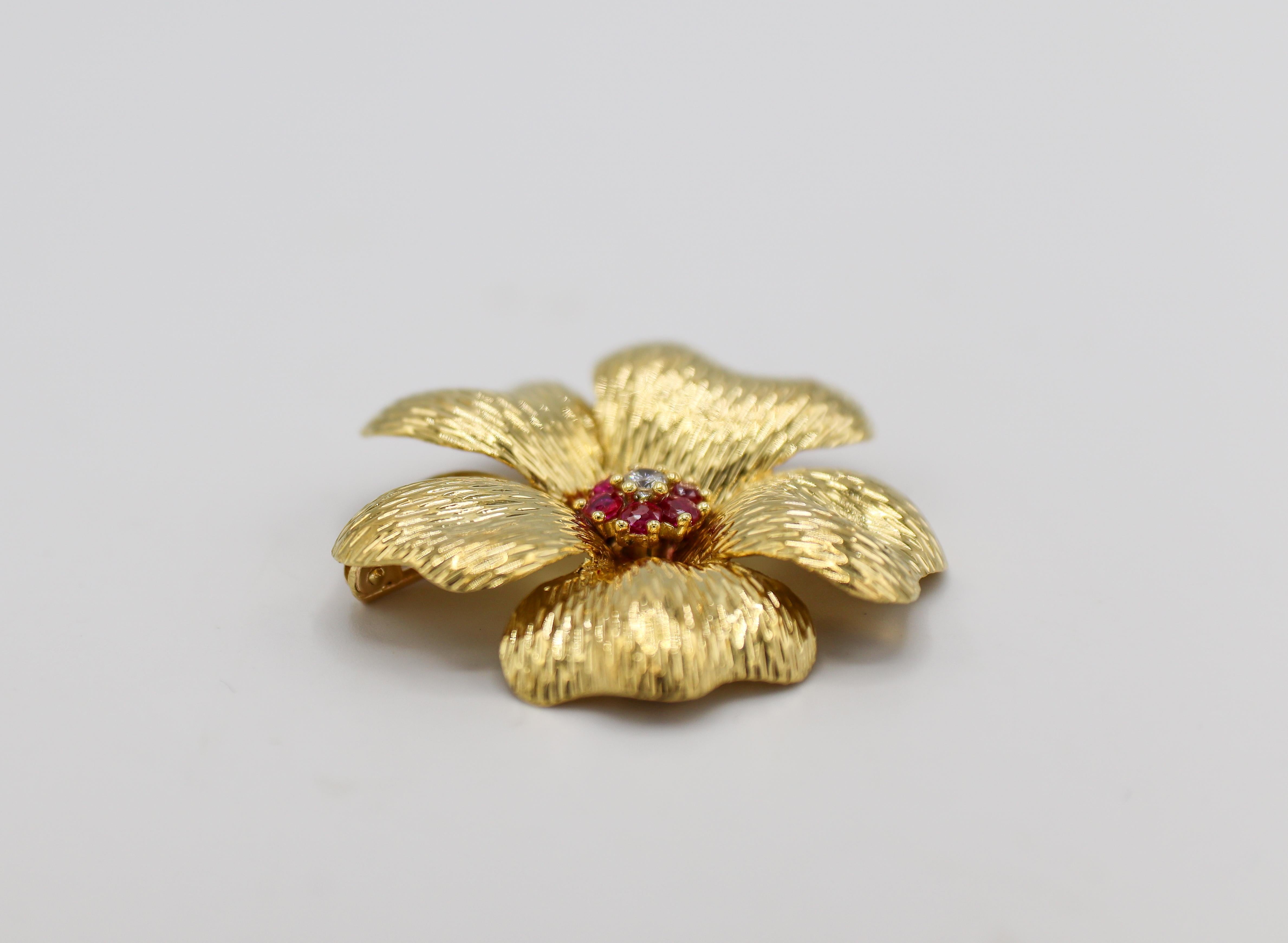 Broche fleur en or jaune 18 carats avec diamants et rubis de Tiffany & Co
Métal : or jaune 18k
Poids : 11,23 grammes
Diamants : diamant rond de 0,05 ct G VS
Dimensions : 37.5 x 37,5 mm
Signé : TIFFANY & CO 18KT ITALY