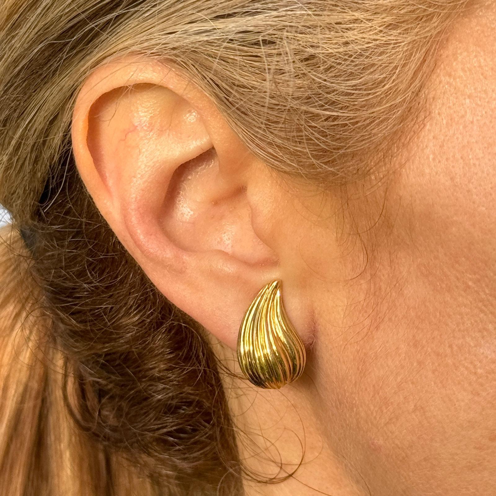 These late 20th-century Tiffany & Co. earclip earrings exude timeless sophistication with a touch of bold elegance. Crafted from rich 18k yellow gold, each earring features a fluted, ribbed design that creates a dynamic play of light across the
