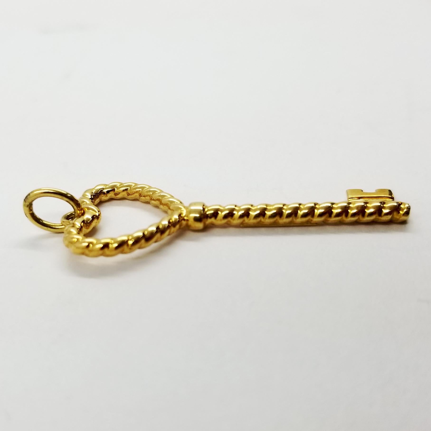 This elegant pendant from Tiffany and Co is crafted in 18 karat yellow gold. The key design features a rope texture with the shape of a heart at the top. The entire pendant swings freely from a simple bale. The back is engraved T&Co 750 Italy. The