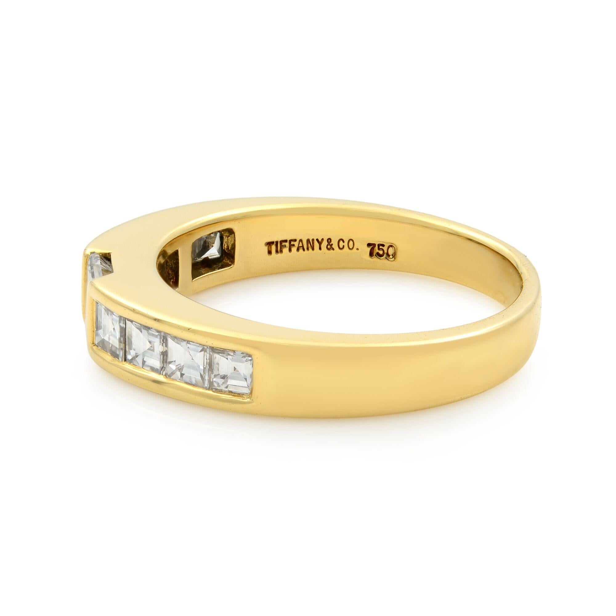 This lovely vintage stack band ring from Tiffany & Co is crafted from solid 18k yellow gold in a fine polished finish. Channel set with 9 princess cut diamonds. Center stone weights 0.29cts and side stones are 0.48cts. Diamond color F-G and VS