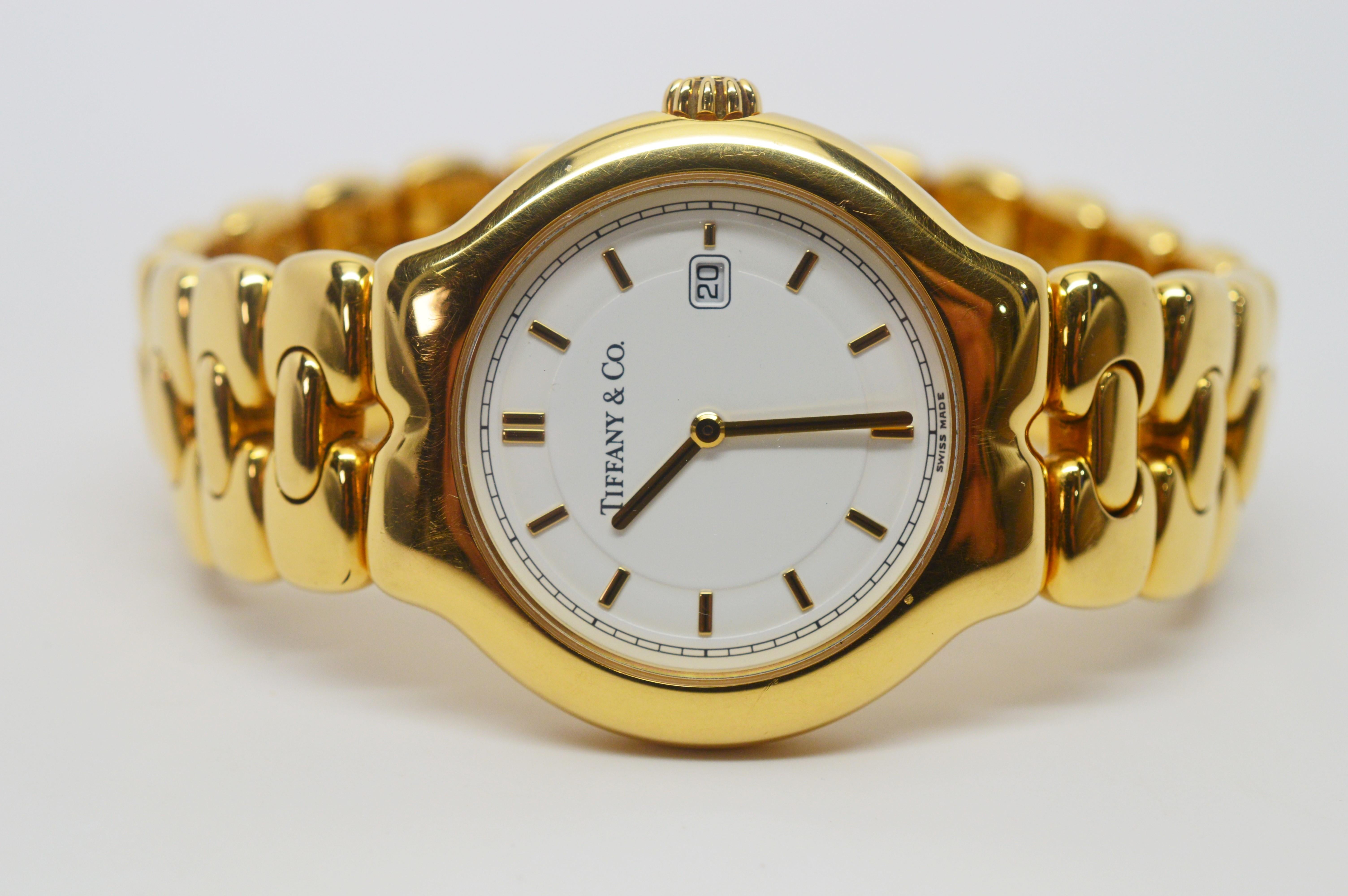 By Tiffany & Co. for the Tesoro Collection, in minty condition, this fine wrist watch is in eighteen karat 750 yellow gold with an easy to read white dial and gold match stick markers and date window. The case is 33mm crown x 35mm. The quality