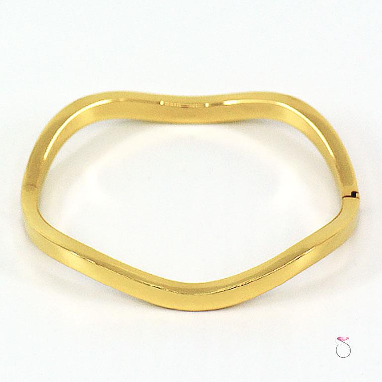 Authentic Tiffany & Co. wave hinged bracelet is 18K yellow gold. This beautiful bracelet has a very modern wave design with high polish mirror finish. The bracelet is hinged for easy use. The bracelet has an inside diameter of 2.25 inches and inside