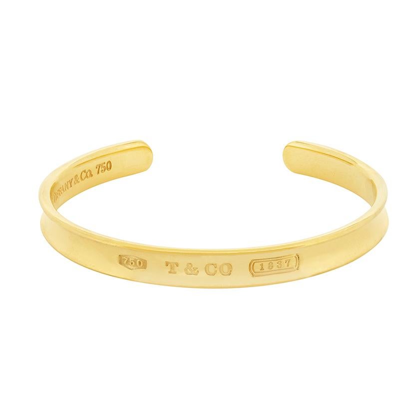 This is a classic Tiffany & Co. '1837' Cuff. It is made of solid 18 carat gold and has an engraved 'T & Co.' on display. This bracelet has all original Tiffany & Co. hallmarks, and was made in 1997.  
Metal: 18ct Yellow Gold
Age: Modern,