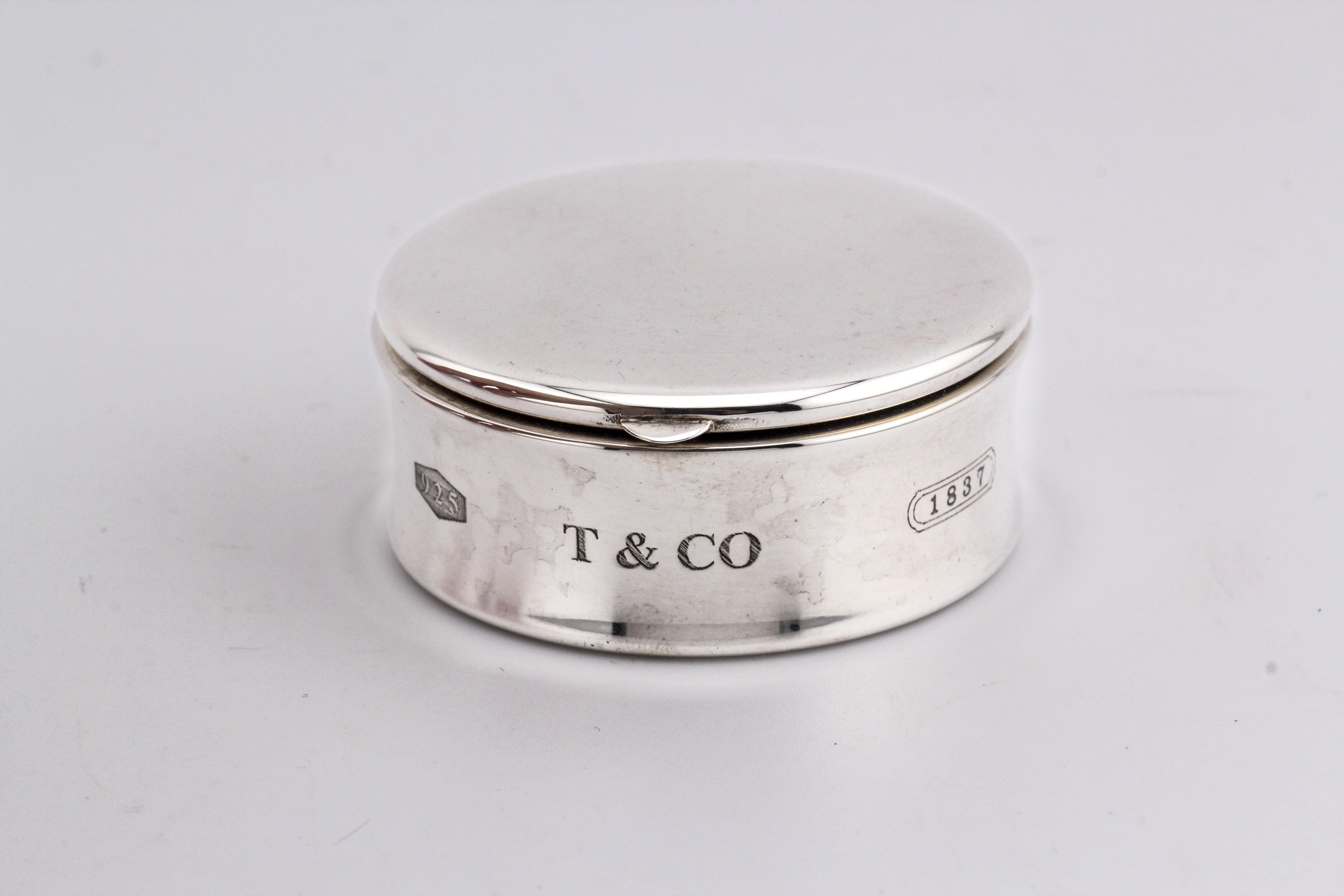 La boîte à pilules ronde en argent 925 de Tiffany & Co. 1837 est un accessoire élégant et sophistiqué, incarnant l'élégance intemporelle qui fait la renommée de Tiffany & Co. Cette boîte à pilules fait partie de l'emblématique Collection 1837, qui