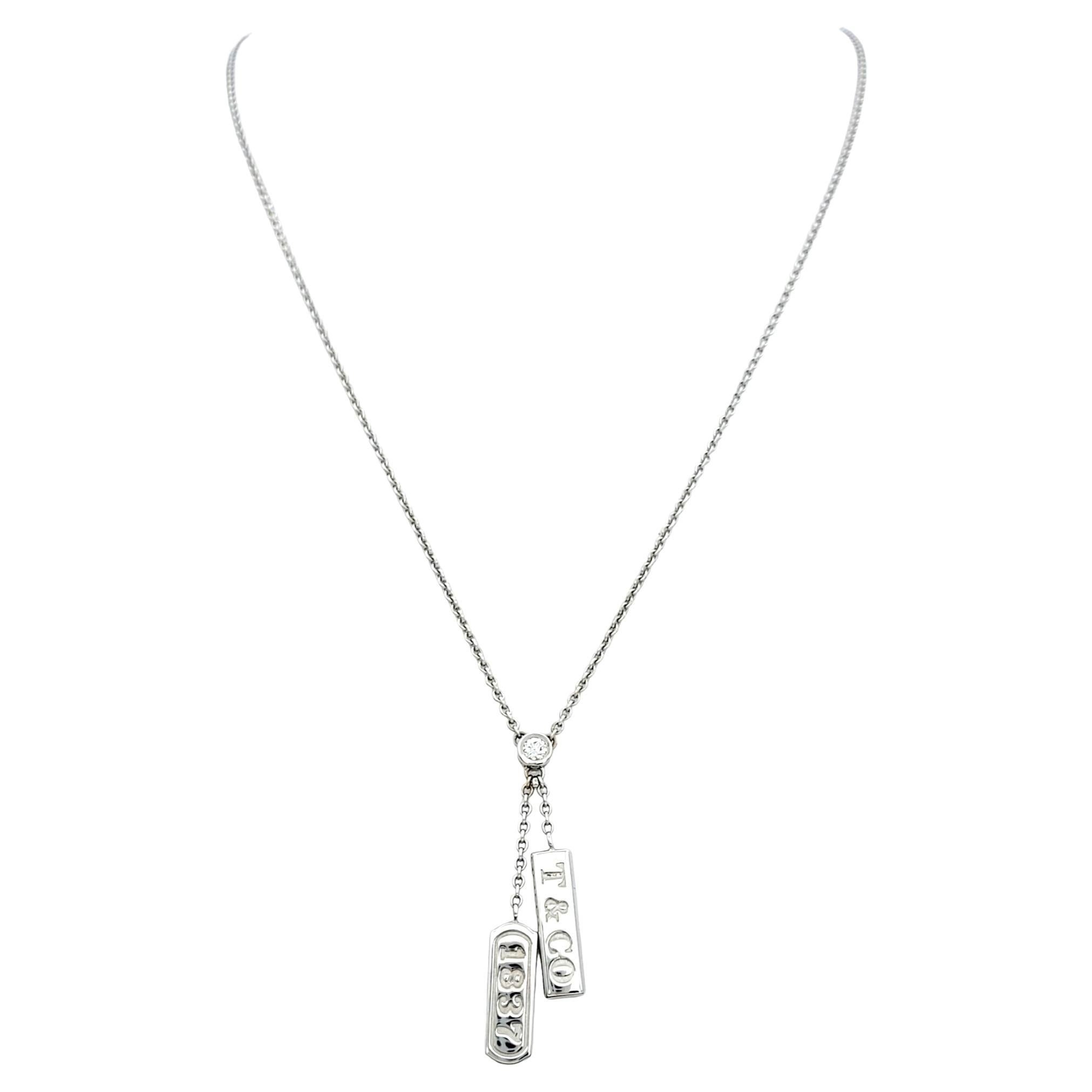 This classic Tiffany & Co. pendant necklace is simple yet elegant. The 18 karat white gold chain is both delicate and durable, making it perfect for everyday wear or special occasions.

The stationary pendant, featuring two slender bars engraved