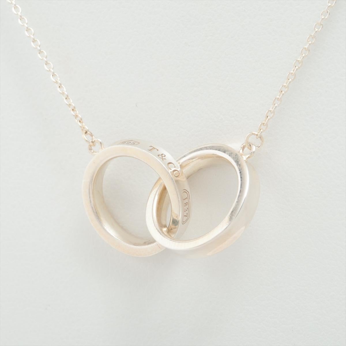 The Tiffany & Co. 1837 Interlocking Circle Necklace in Silver is a sleek and sophisticated accessory that embodies the brand's legacy of timeless elegance. Crafted from high-quality sterling silver, the necklace features two interlocking circles,