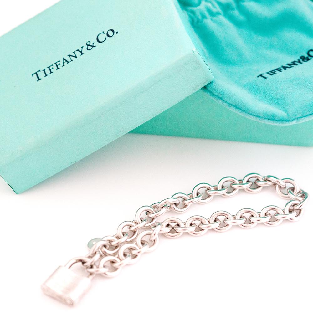 The Tiffany & Co. 1837 Padlock Charm Silver Bracelet is a classic and sophisticated piece that embodies the timeless elegance and exquisite craftsmanship associated with the Tiffany brand. This bracelet features a sleek, sterling silver chain linked