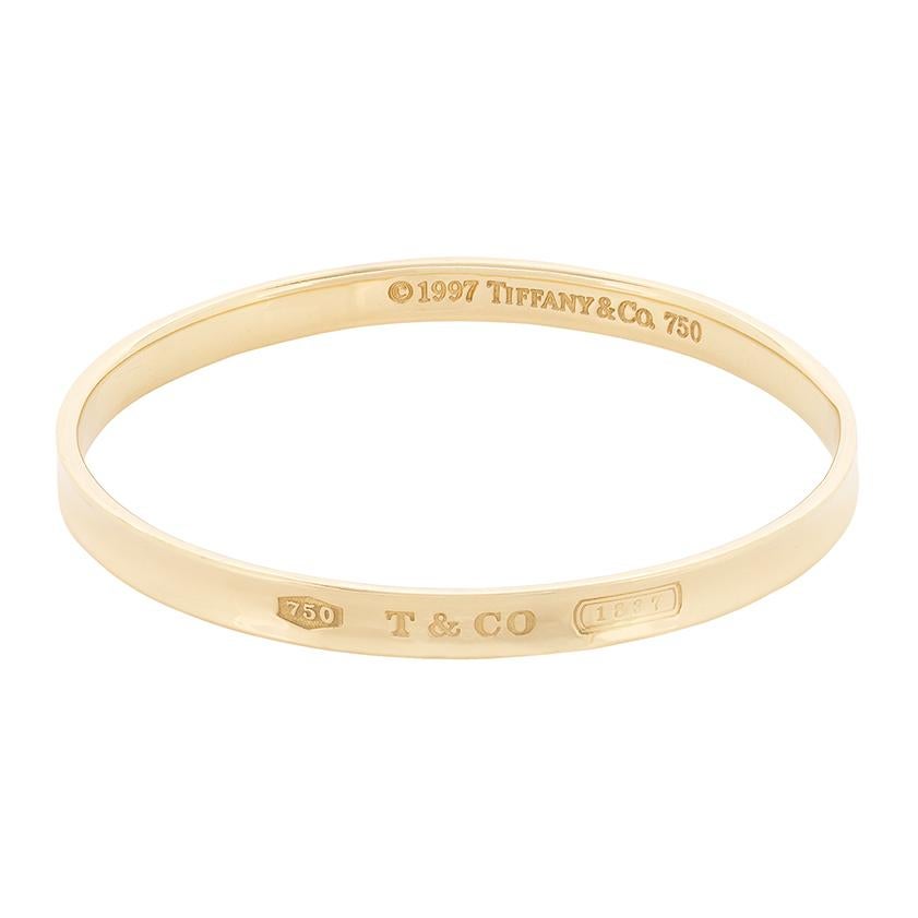 Dating to the late 1990s collection from Tiffany & Co, this solid gold bangle is made from 18 carat yellow gold. It is part of their '1837' collection, which celebrates the birth of Tiifany & Co. It is a simple design, made to worn everyday. It has