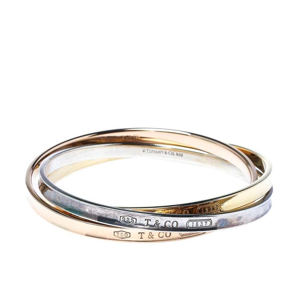 A lovely rendition of a bangle, this by Tiffany & Co. is brilliant in design and appeal. The bracelet has interlocking circles in silver, 18k yellow and rose gold graced with signature engravings that bring to mind the brand's fruitful