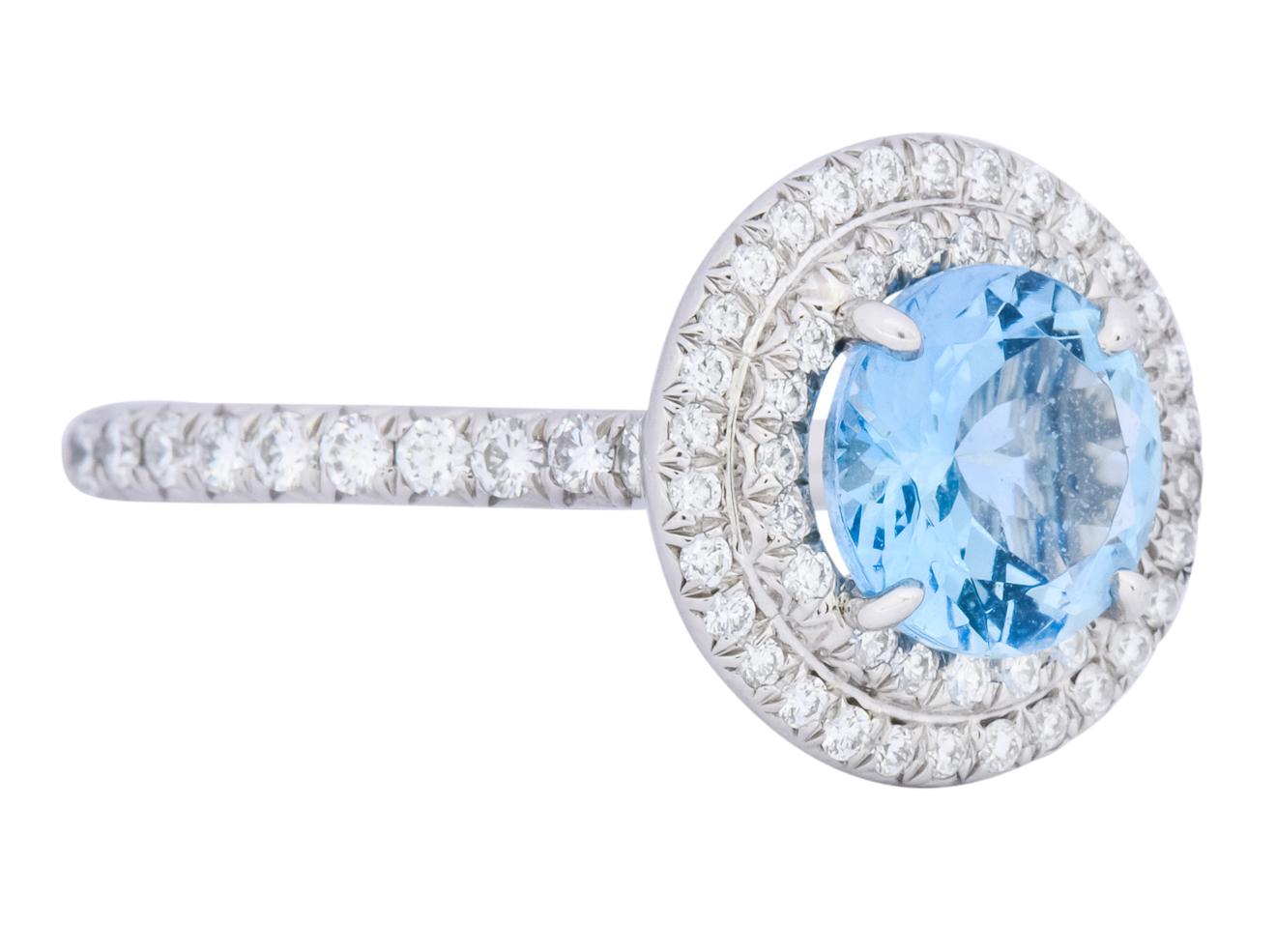 Centering a round cut aquamarine weighing approximately 1.25 carat, transparent medium-dark sea blue in color

Surrounded by a double halo and shoulders bead set with round brilliant cut diamonds weighing approximately 0.60 carat total, F/G color
