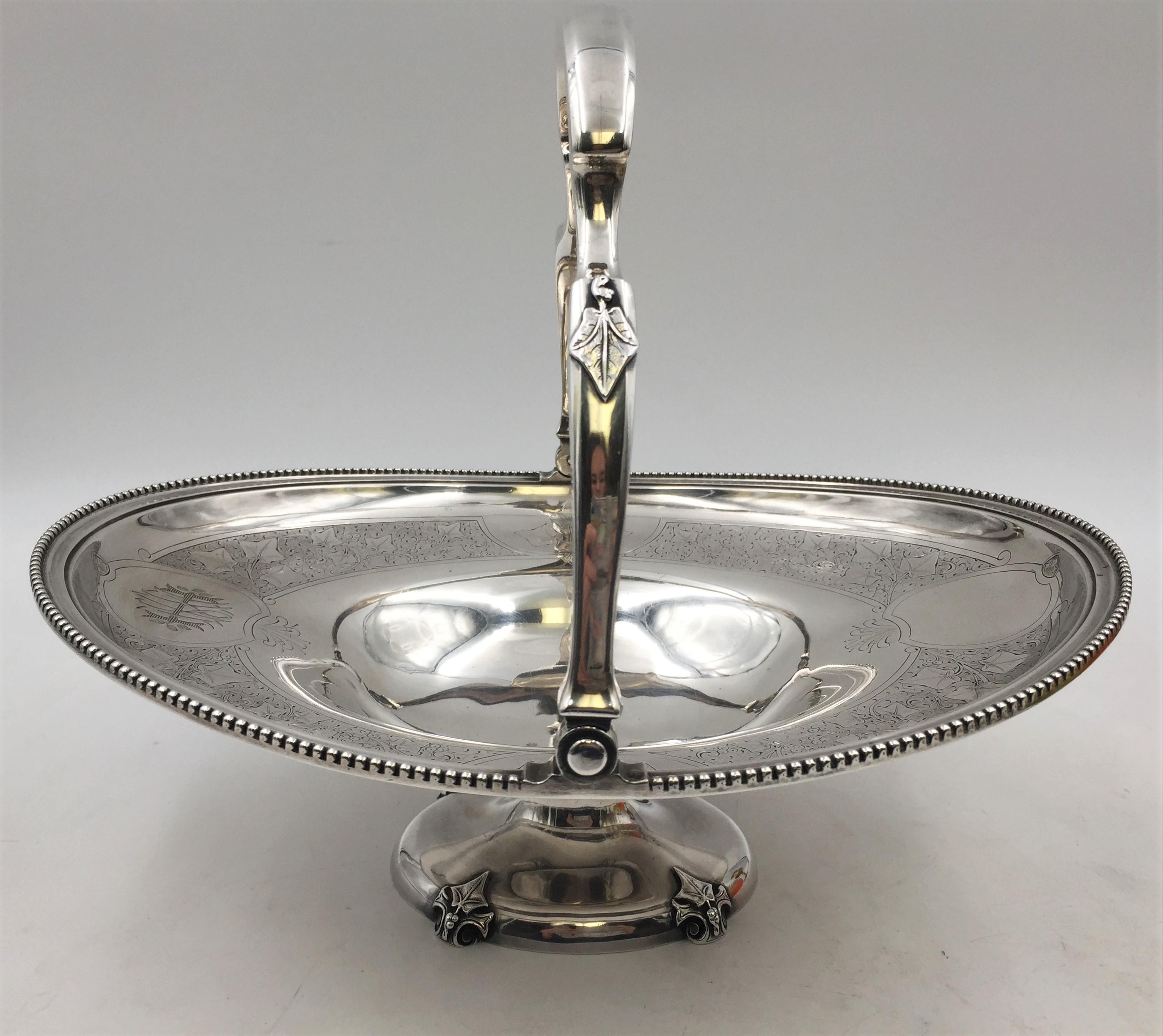 Tiffany & Co. sterling silver basket / centerpiece bowl in pattern number 1721 from the late 1860s with a beaded rim, a handle and base with applied leaves, and engraved vegetal and twirling motifs near the rim. It measures 10'' in height with the