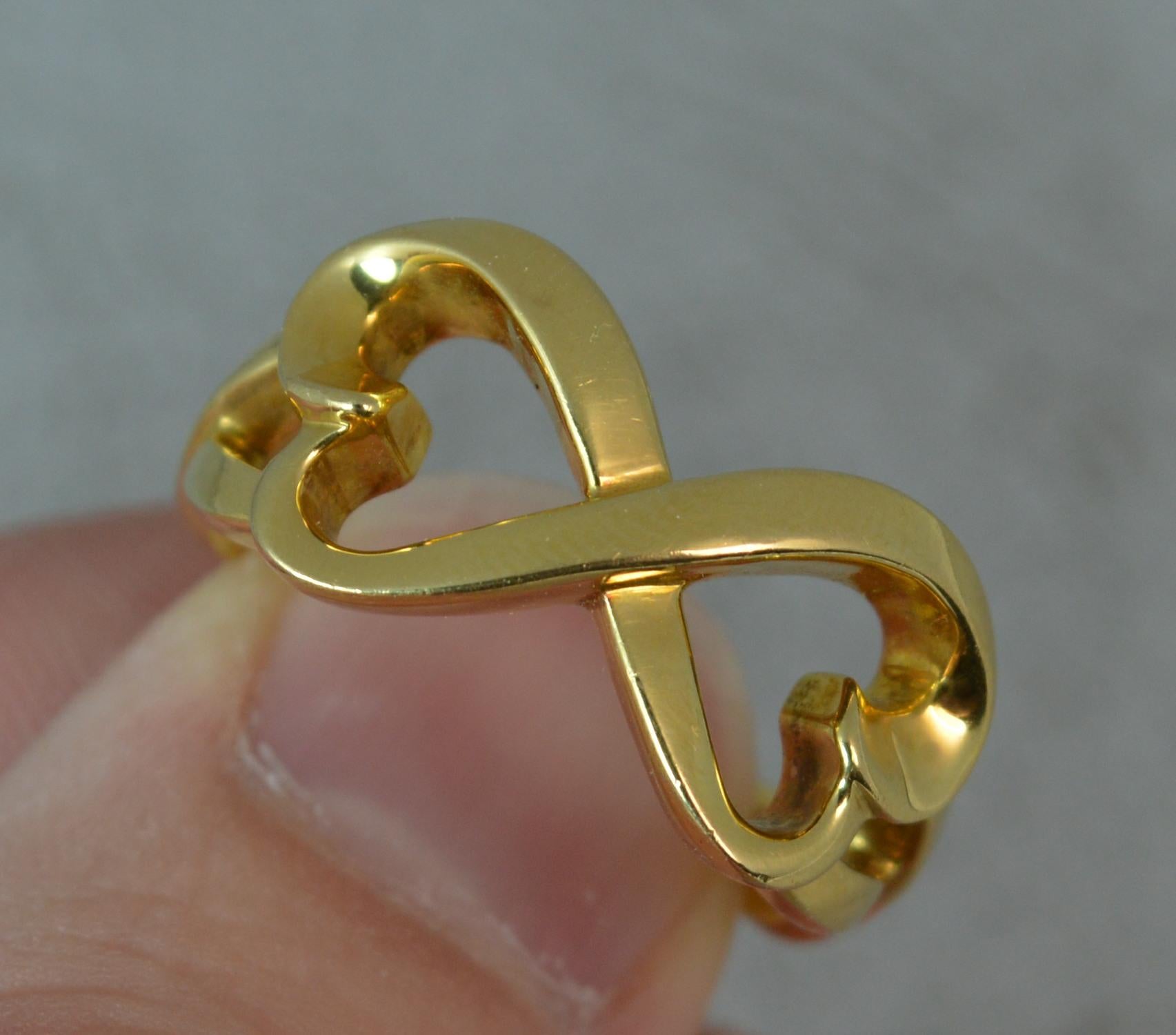 A Tiffany and Co 18 carat yellow gold ring.
SIZE ; R 1/2 UK, 9 US
Double twined heart shape design. 22mm x 11mm head.
Well made, good gauge of gold.

CONDITION ; Very good. Crisp pattern. Clean and solid shank. With pouch etc. Please view
