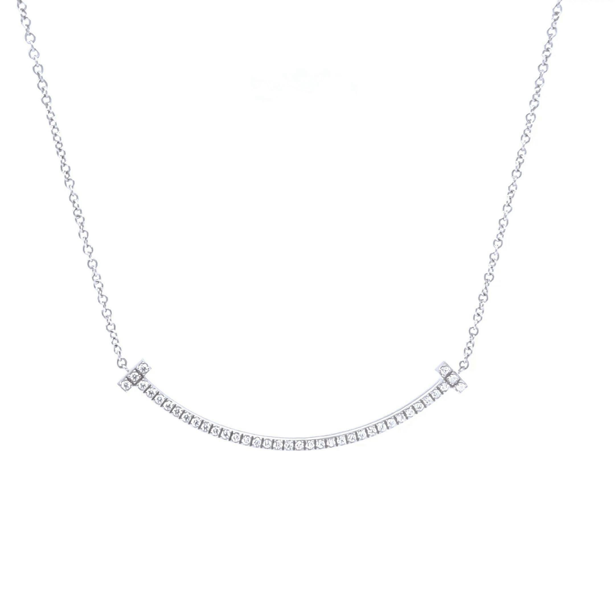 Cet élégant pendentif T Smile de Tiffany est réalisé en or blanc 18 ct, délicatement incurvé dans le motif en 