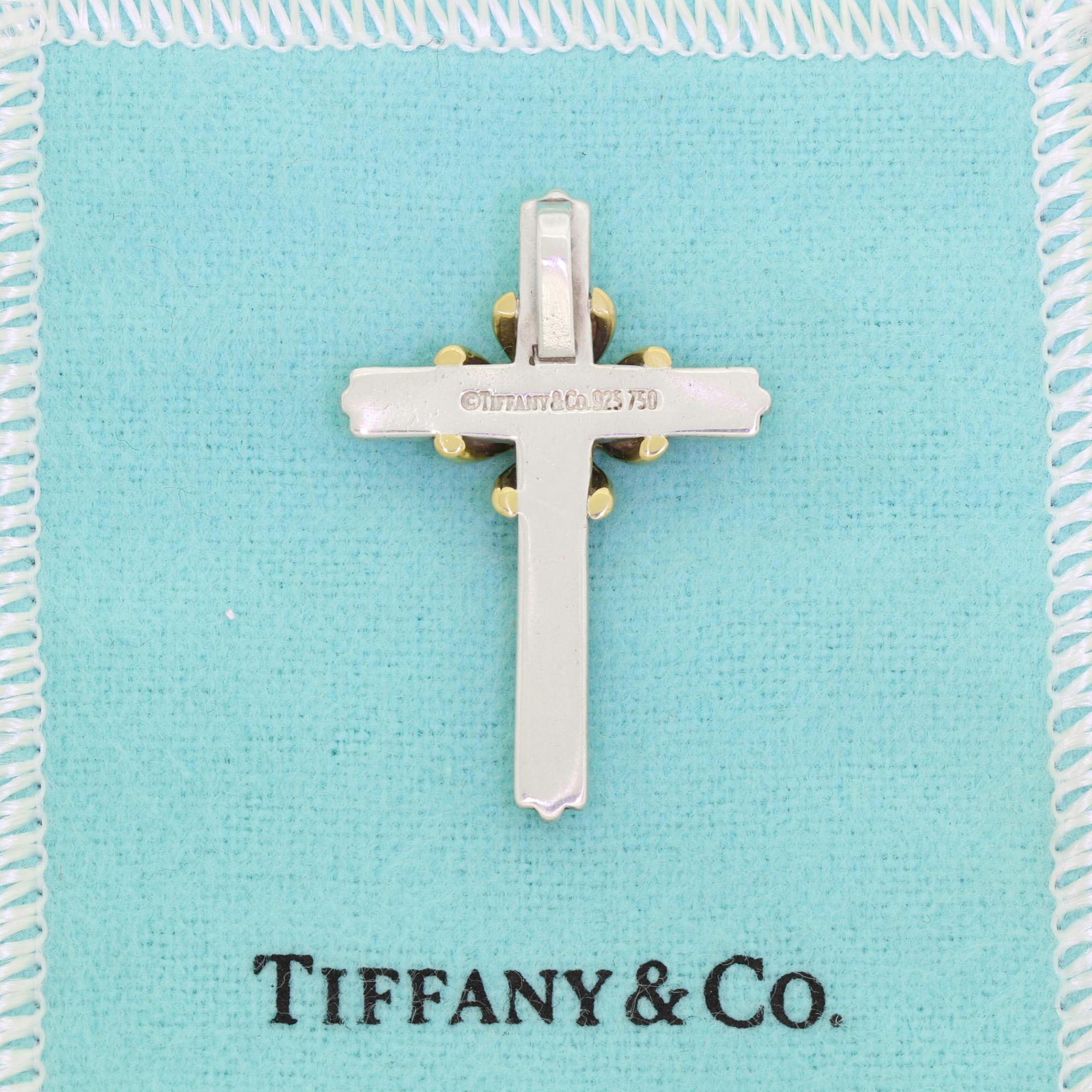 This stunning Tiffany & Co cross pendant is crafted from 18K yellow gold and fine sterling silver. Featuring an ornate ridged design of the finest craftsmanship, this is a truly beautiful way to display your faith. The central gold accent provides a