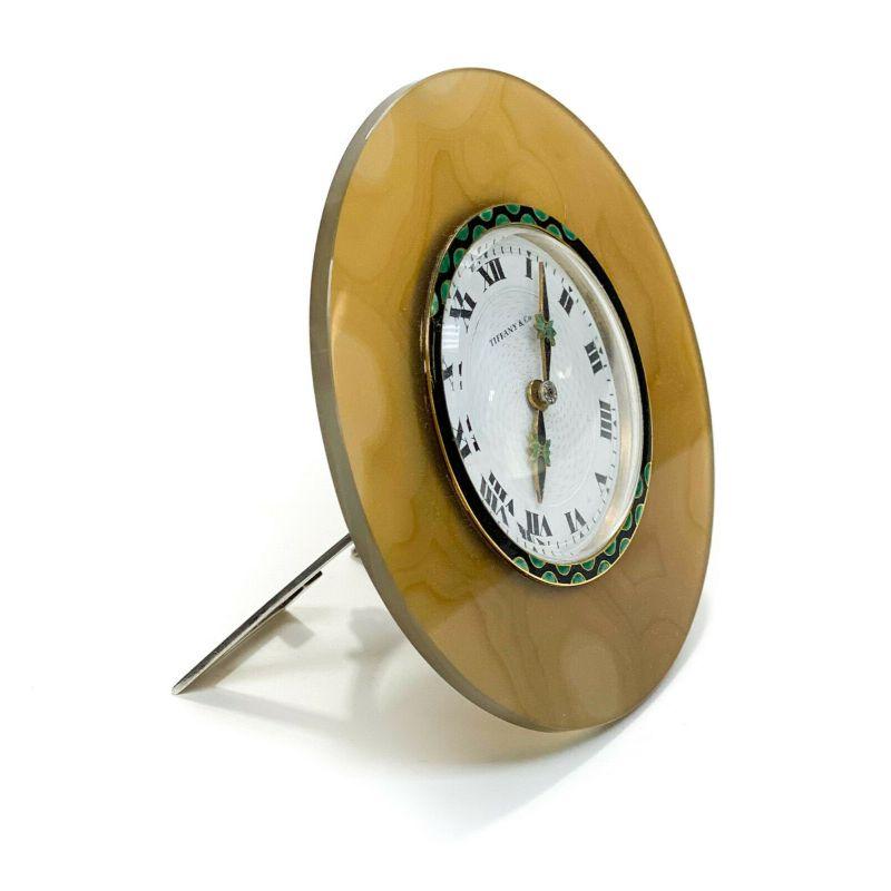 Tiffany & Co. 18k gold agate enamel diamond & sterling silver Art Deco Clock

A very fine Art Deco desk clock by Tiffany & Co., circa 1930. Consisting of a carved round agate frame, mounted to an 18k gold and enamel bezel clock. Gold and enamel