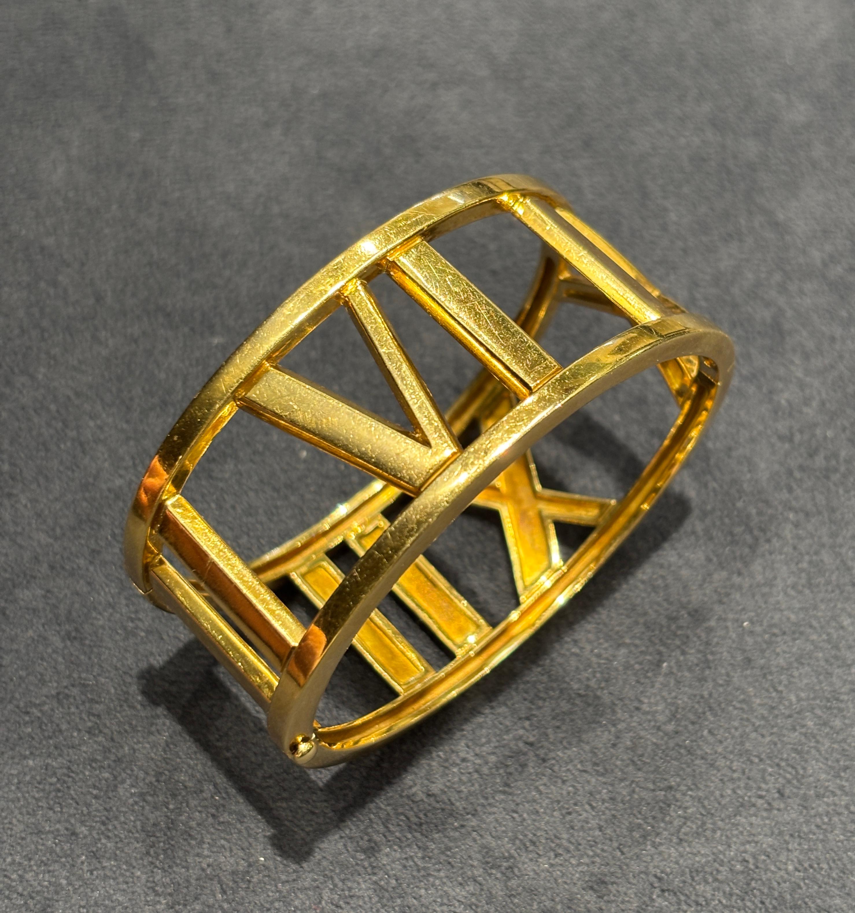 This hefty 18k yellow gold Atlas bangle by Tiffany & Co dates back to 2003. It incorporates the Roman numerals III, VI, IX, XII in its design. The bangle measures 2.8cm in width and 19cm in circumference.