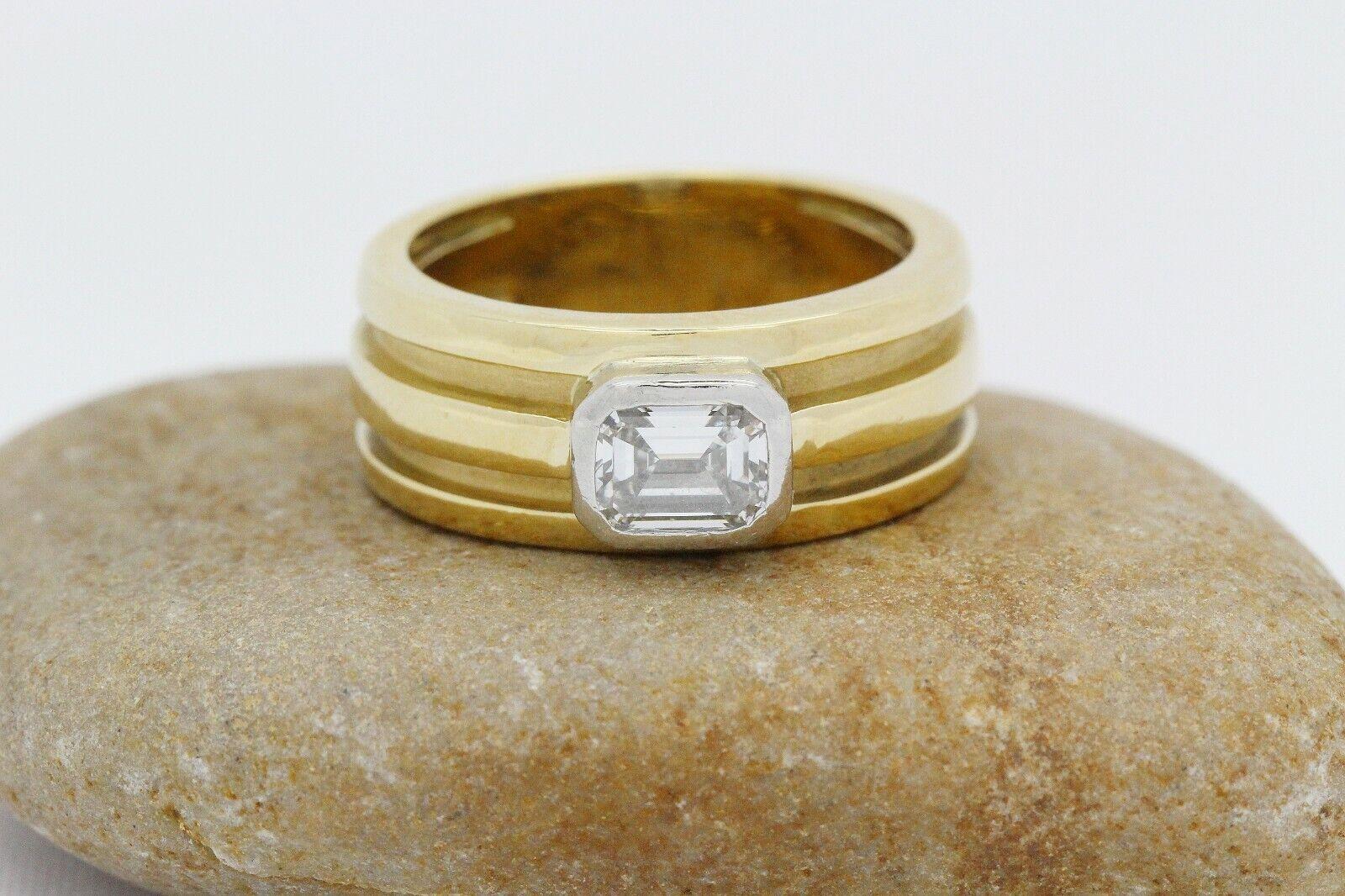 This lovely Tiffany & Co. vintage diamond ring from 1995, is crafted in vibrant 18k yellow gold. This classic piece features a beautiful emerald cut diamond at the center of a wide, ridged band, set horizontally along the ring, resting within a