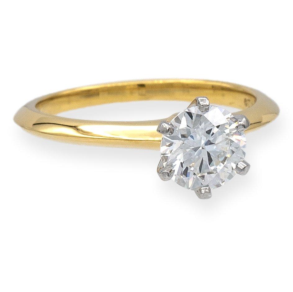 Tiffany & Co. classic solitaire engagement ring finely crafted in 18 karat yellow gold featuring a round brilliant diamond center weighing .91 carats I color , VS1 clarity set in a platinum 6 prong basket setting. Diamond is considered triple X
