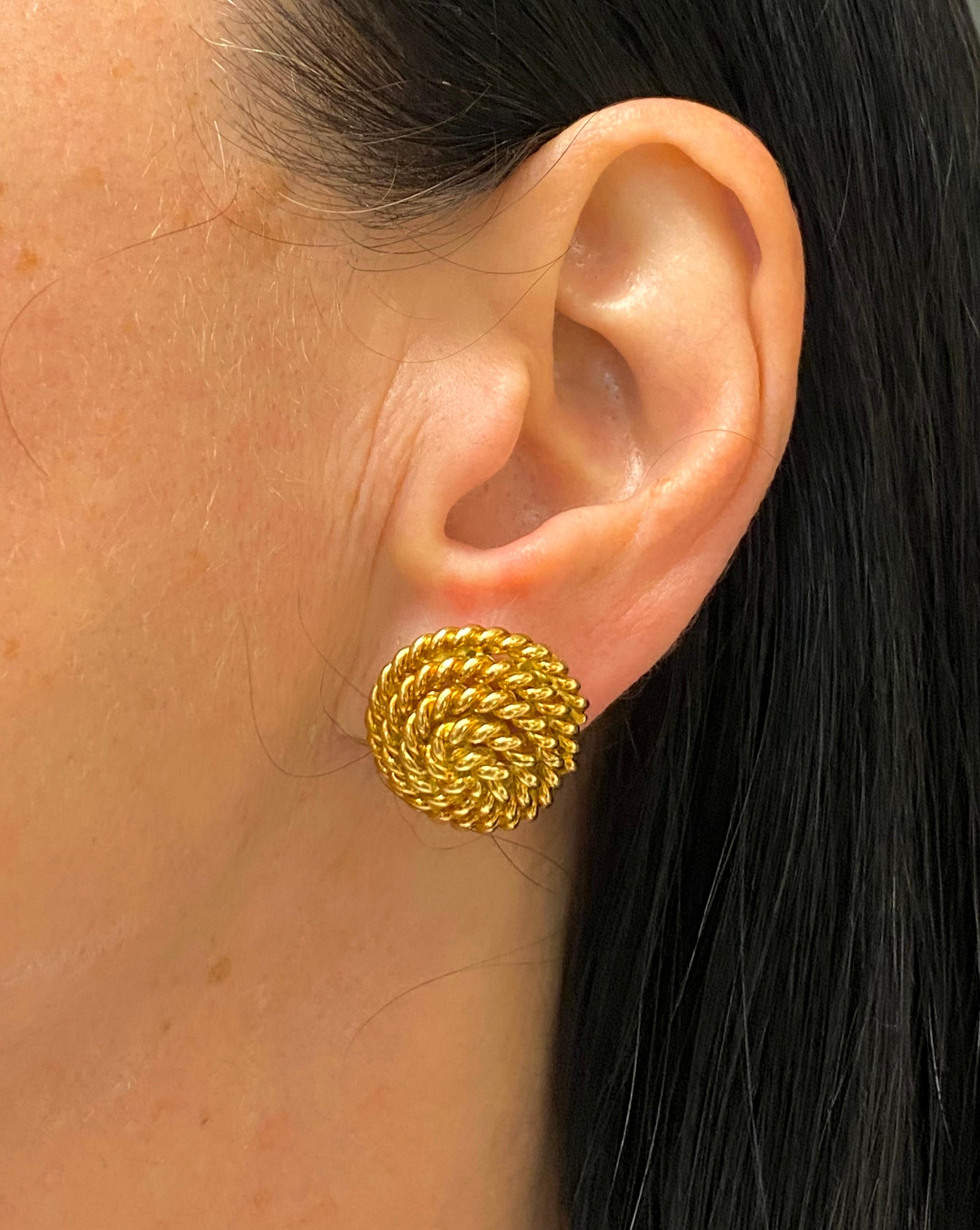 A pair of rope earrings by Tiffany & Co. made in 18k gold. The earrings have a convex shape,
with a gold rope being staged as a swirl. The gold is polished and braided which makes the
earrings look shiny and glossy. The round shape is a reference to
