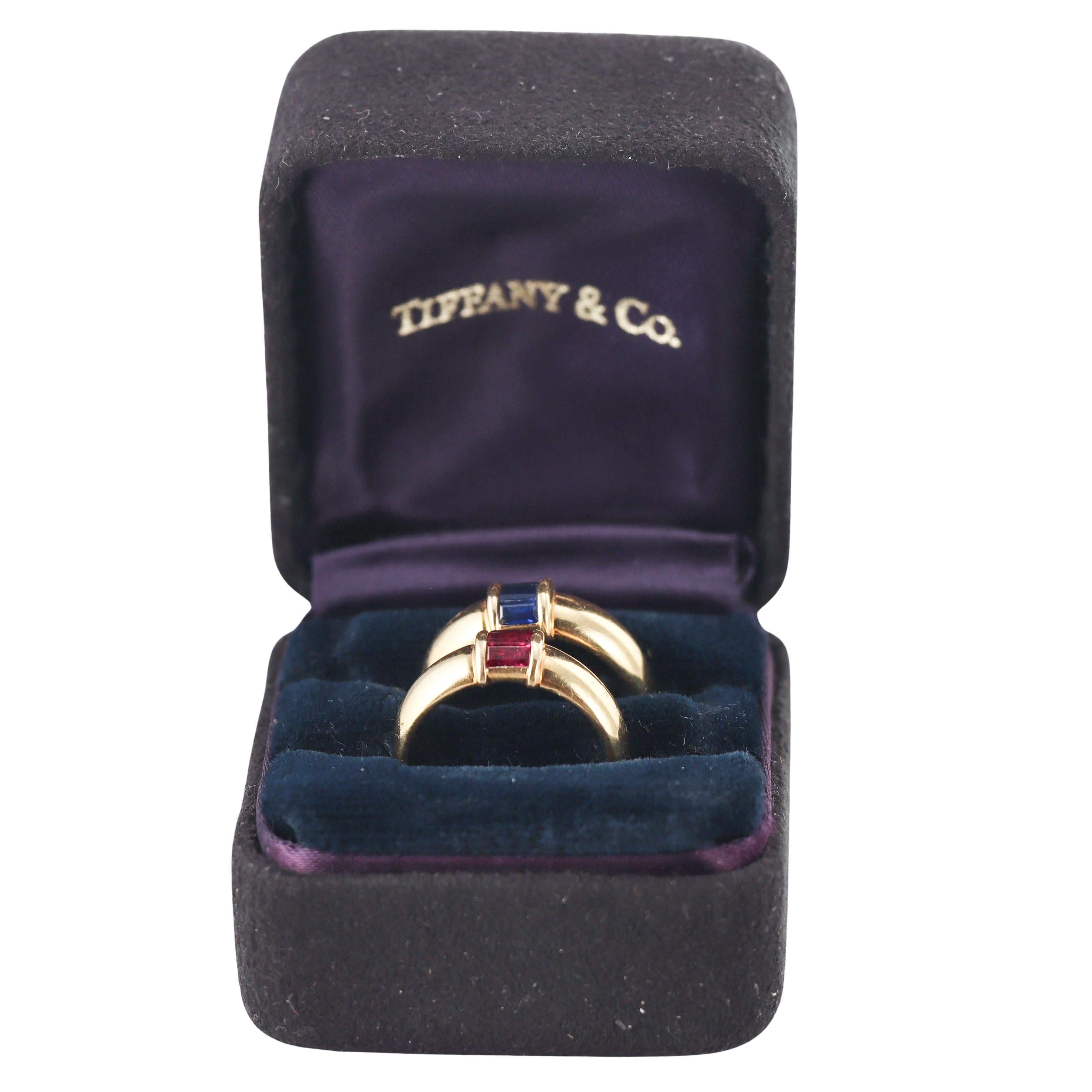 Coppia di anelli impilabili in oro giallo 18k di Tiffany & Co., uno con zaffiri e l'altro con rubini. Possono essere indossati insieme impilati o separatamente.
Ogni anello è una misura 6 ed è largo 6,8 mm nella parte superiore.
Gli anelli sono