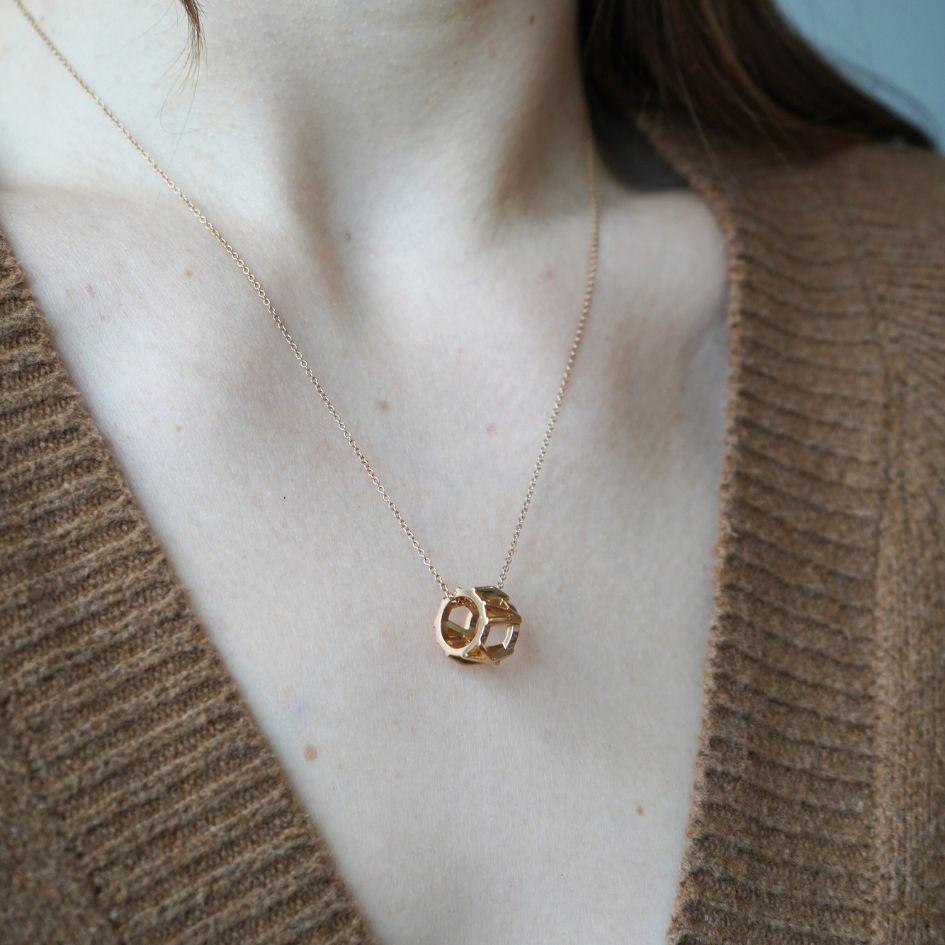 This Tiffany & Co. pendant necklace is part of the Atlas® collection, introduced in 1995, this particular piece is from the early 2000s. Crafted in 18k rose gold, the design features a wide, openwork circular pendant adorned with Roman numerals “X,”