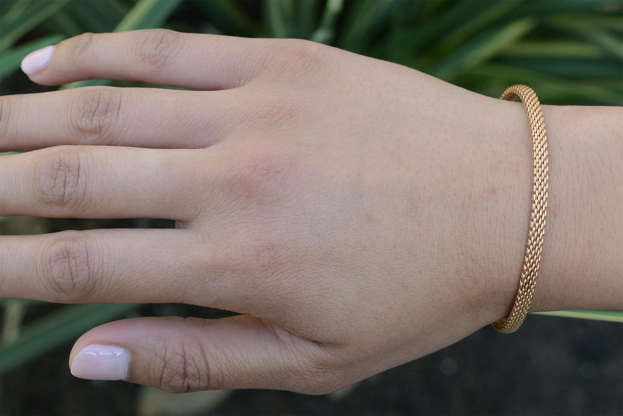 Un bracelet vintage incroyablement rare de Tiffany and Co. doté d'un cadre étroit qui se glisse confortablement sur le poignet. Le motif de maille caractéristique fait le tour complet du bracelet et est composé d'or rose 18 carats. Il s'agit d'un