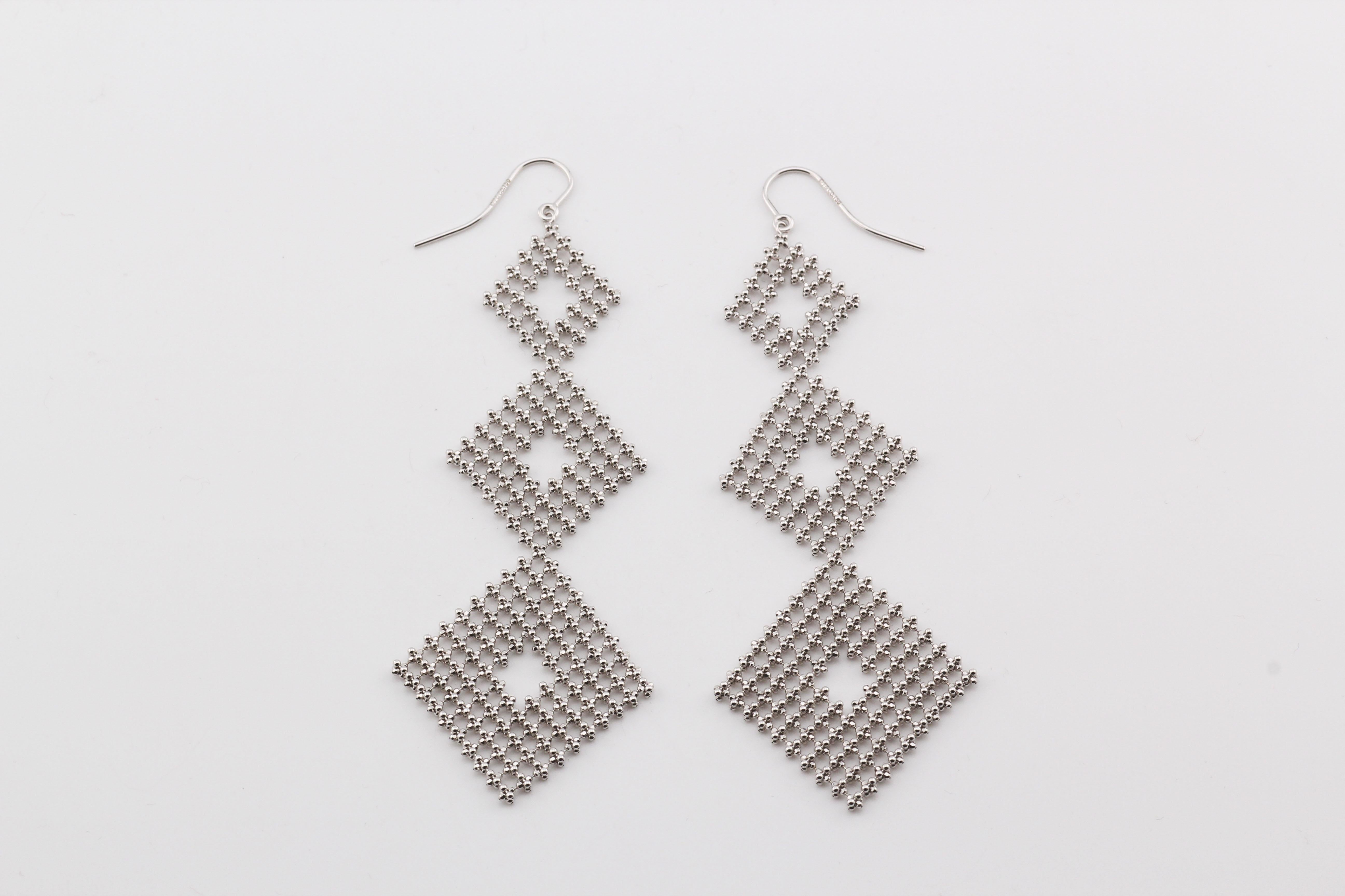 The Tiffany & Co. 18K White Gold Bead Mesh Drop Earrings are an exquisite example of timeless elegance and sophisticated design. Crafted from luxurious 18K white gold, these earrings feature a delicate mesh design composed of intricately woven gold
