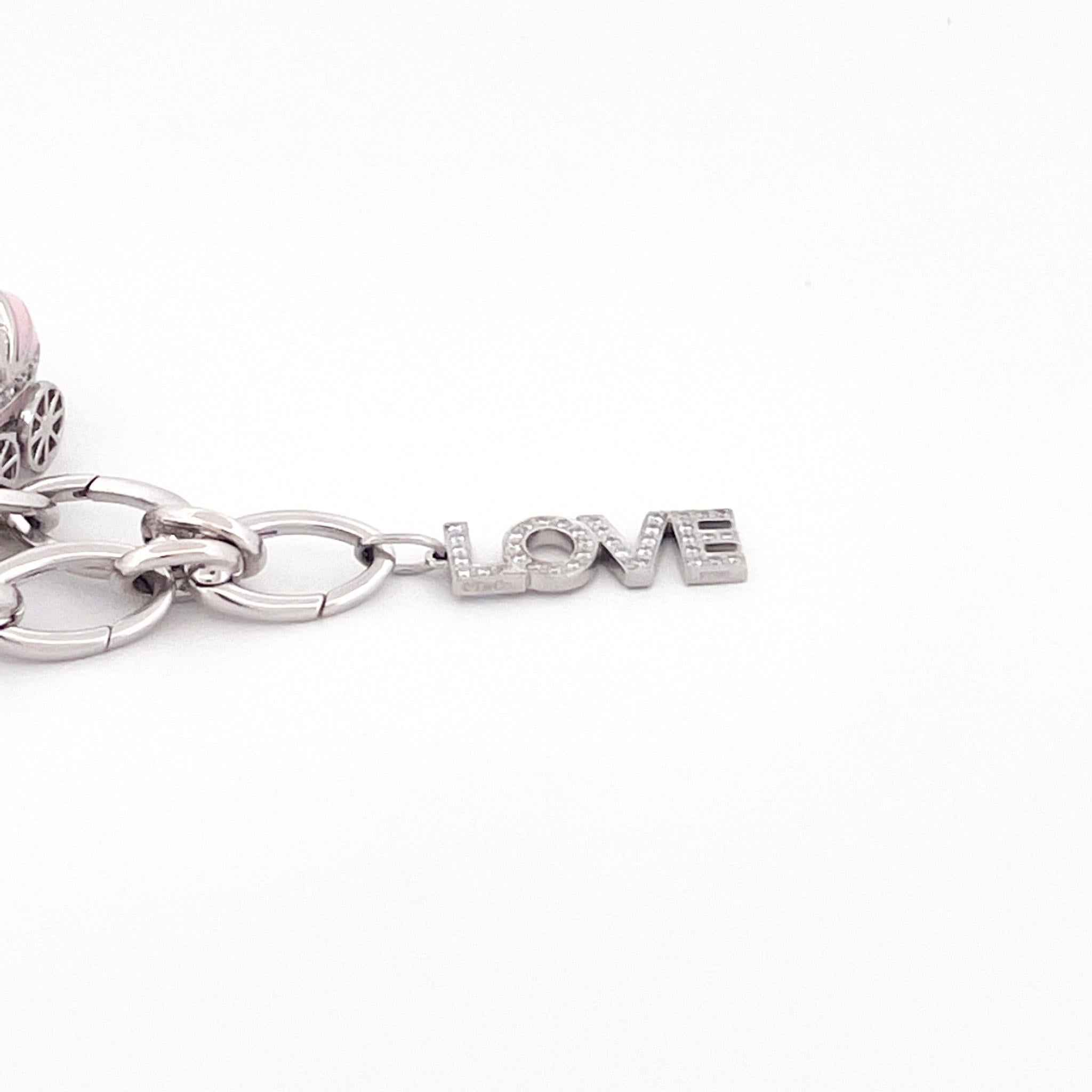 From designer Tiffany & Co., circa 2005, 18 karat white gold oval link charm bracelet. This bracelet is crafted with an assortment of charms including

1 platinum and pink enamel diamond baby carriage charm crafted with 23 round cut diamonds with a