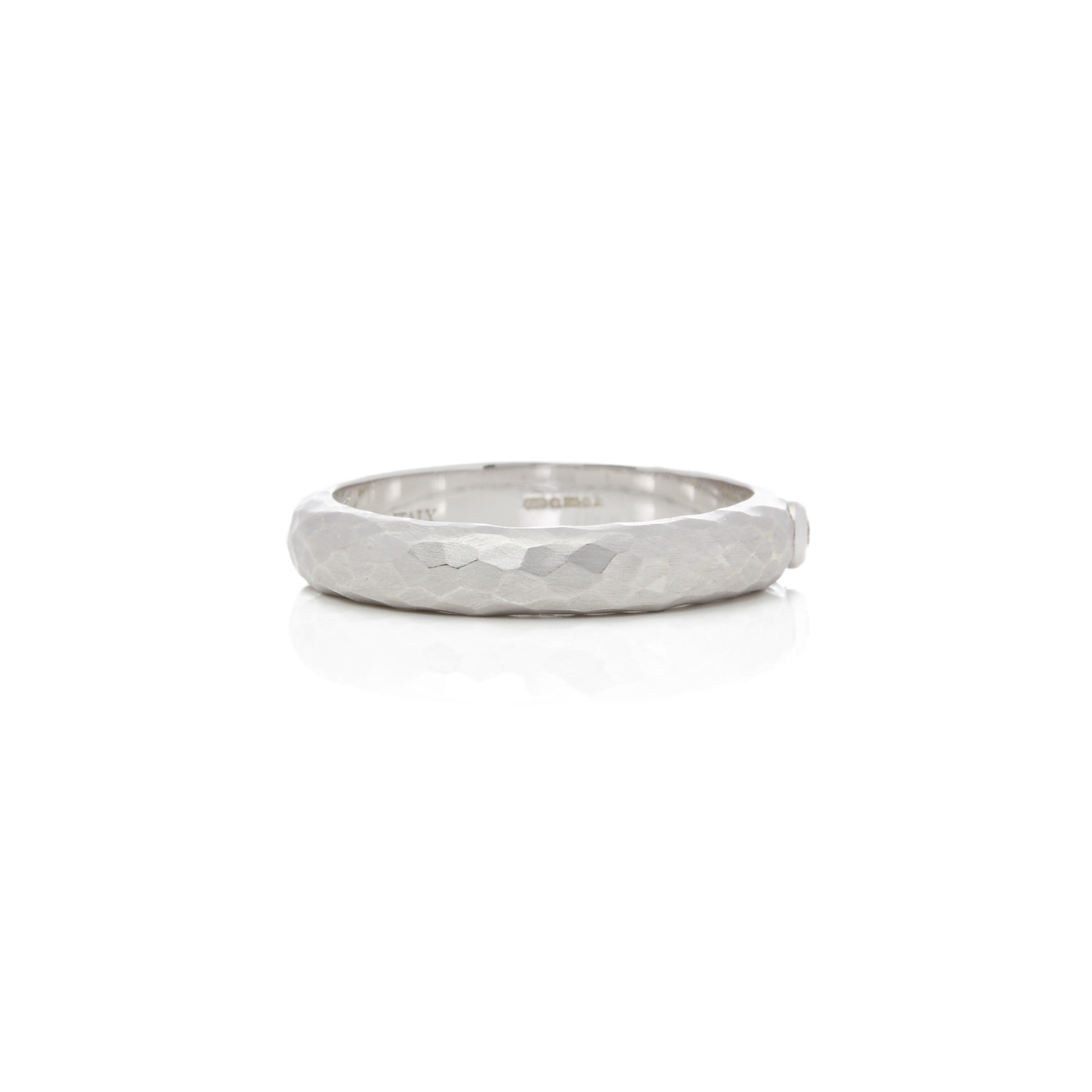 Este Anillo de Tiffany & Co pertenece a su Colección Paloma Picasso y lleva un único Diamante Brillante Redondo Montado en una Banda de Oro Blanco de 18k Acabado Martillado de 4,23 mm. Talla UK T, talla EU 61 1/2, talla USA 9 5/8. Completo con caja