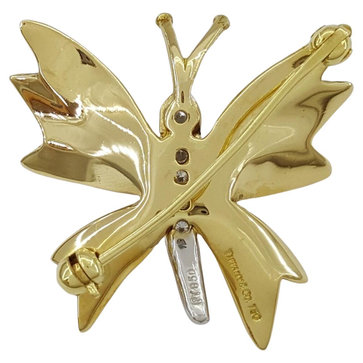 Genuine Tiffany & Co. présente une exquise broche / épingle à papillon en or jaune 18K et platine, ornée d'un diamant rond totalisant 0,09 carats.

Cette magnifique pièce pèse 5,5 grammes et mesure 25 mm de largeur, 24 mm de hauteur et 2,8 mm