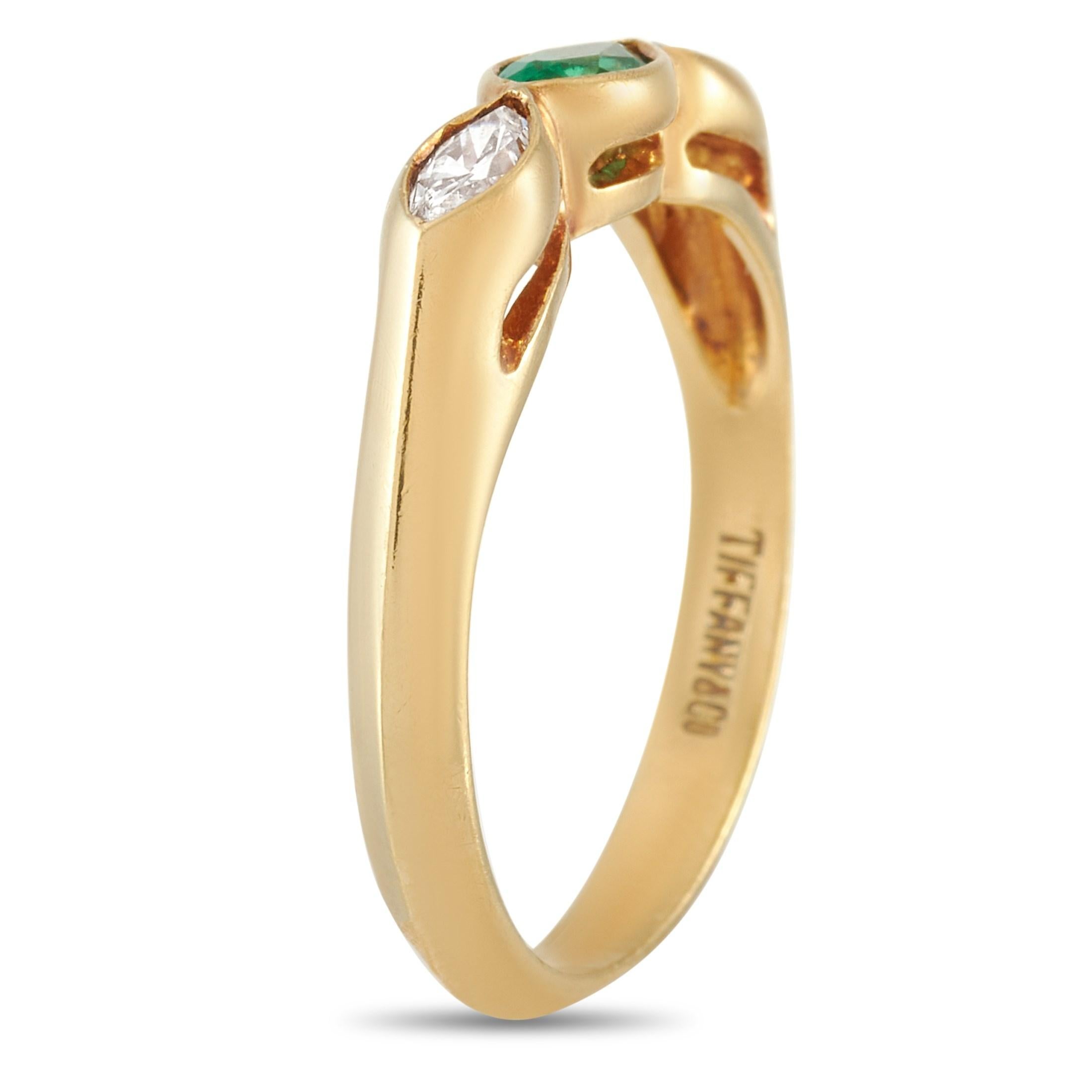 This Tiffany & Co. 18K Yellow Gold 0.25 ct Diamond and 0.25 ct Emerald Ring is made with 18K yellow gold and set with two marquise cut diamonds totaling 0.25 carats on either side of a 0.25 carat marquise cut emerald. The ring has band thickness of