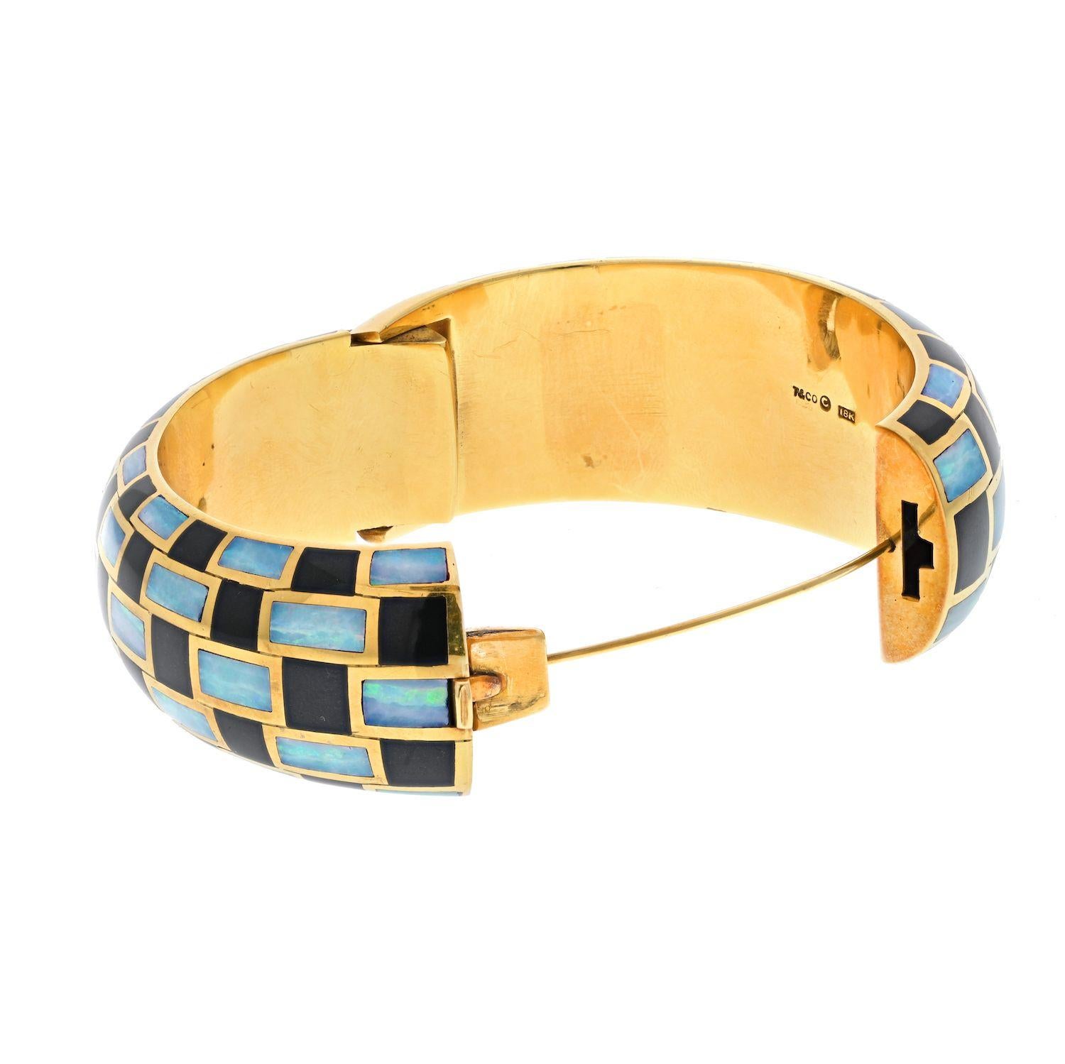 A vintage Angela Cummings for Tiffany & Co. black enamel and opal inlay 18K yellow gold hinged bangle bracelet. Circa 1970.
Wrist size 6 inches (inner circumference 6 inches). 
Width: 0.75 inches. 