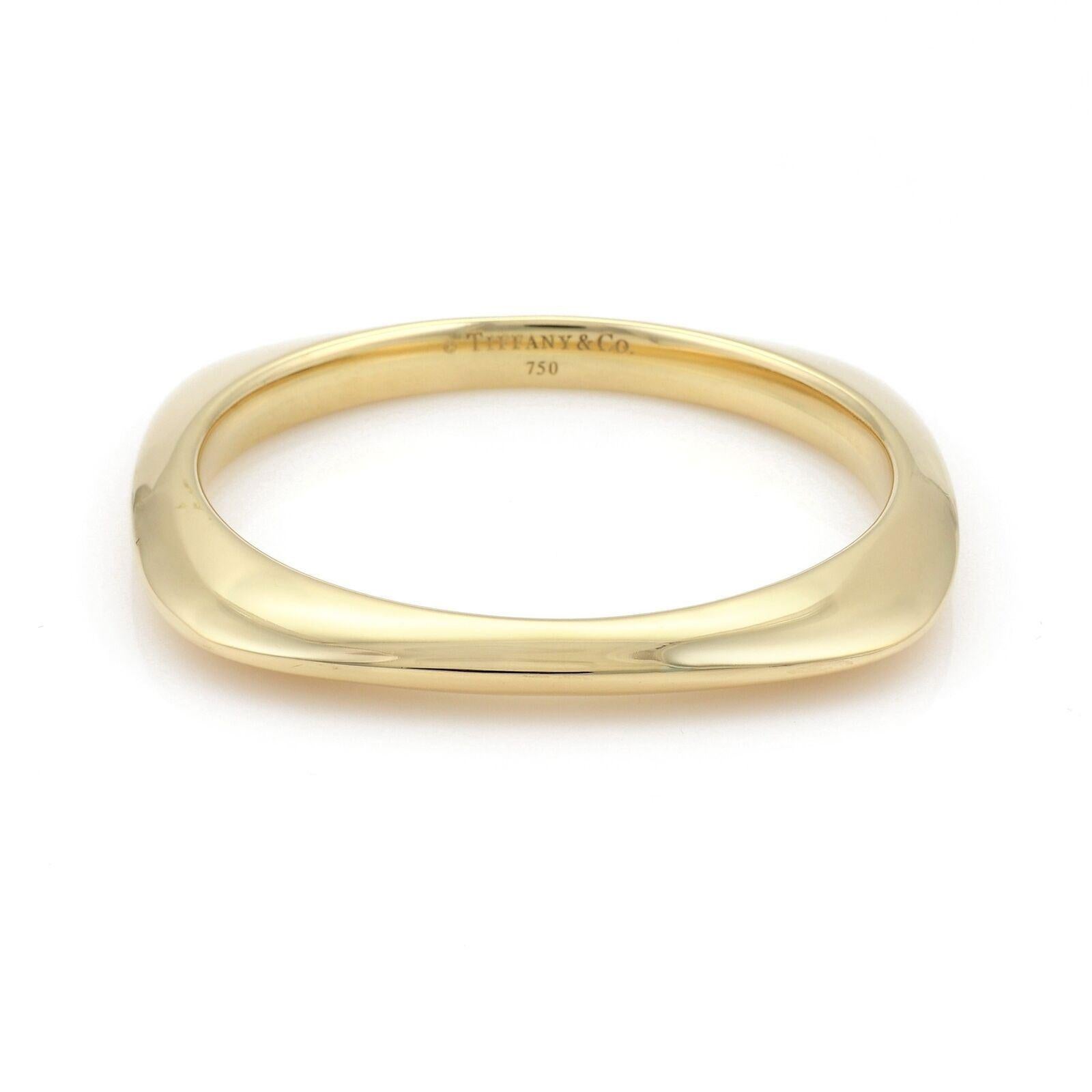 This gorgeous authentic bangle is from Tiffany & Co. It is crafted from 18k yellow gold with a high polished finish featuring a cushion shape frame with the round shape inside for an easier wear. It is signed by the designer with the metal content.