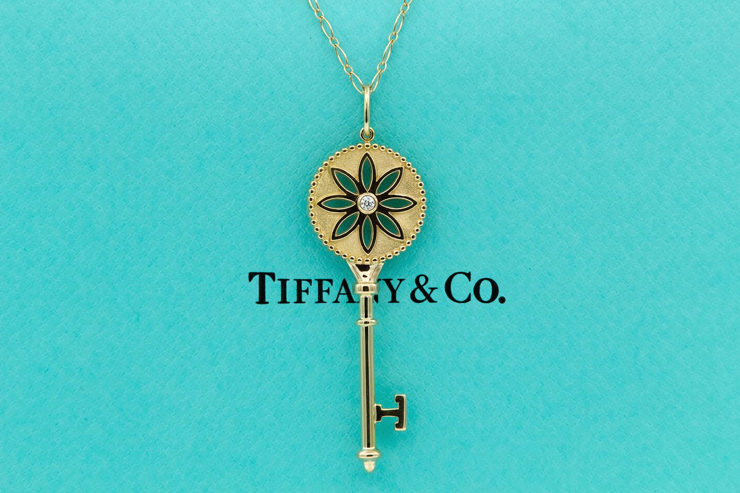 We are pleased to offer this Authentic Tiffany & Co. 18k Yellow Gold & Diamond Daisy Key Large Pendant Necklace. This gorgeous piece features a 2.5 inch 18k yellow gold Tiffany & Co. daisy key pendant set with two 0.08ct round brilliant diamonds on