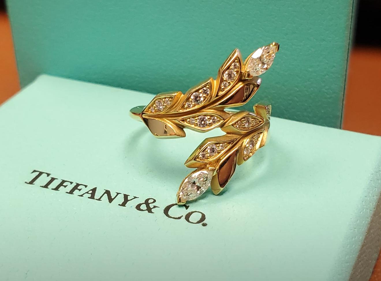 El anillo Tiffany & Co Victoria Vine Bypass es una obra maestra del diseño, bellamente elaborada en oro amarillo de 18 quilates. Este elegante anillo exhibe un exclusivo motivo de derivación en forma de vid, exquisitamente engastado con diamantes