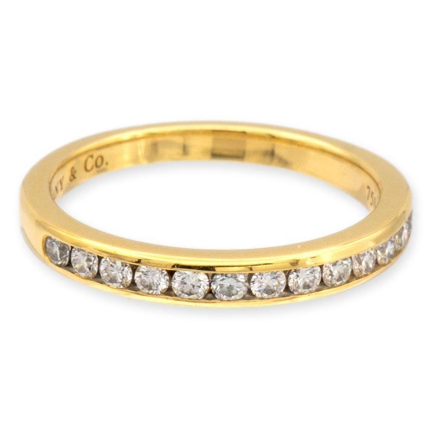 Tiffany & Co. wedding/anniversary band finely crafted in 18 karat yellow gold with 15 channel set round brilliant cut diamonds weighing 0.24 carats total. Fully Hallmarked with logo and metal content.

Ring Specifications
Brand: Tiffany & Co.
Style;